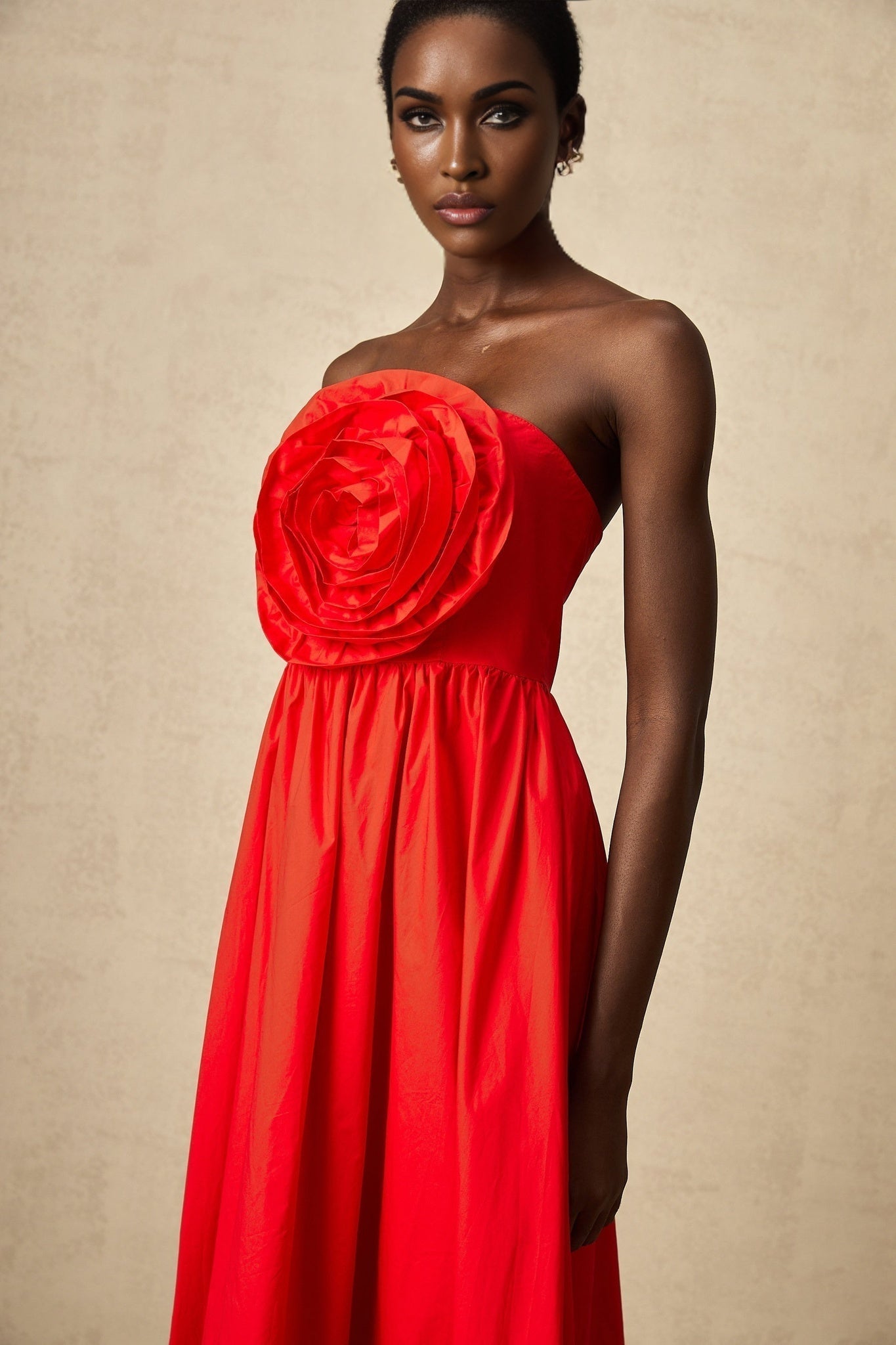 Woman wearing long red maxi dress with ruffled 3d petal details
