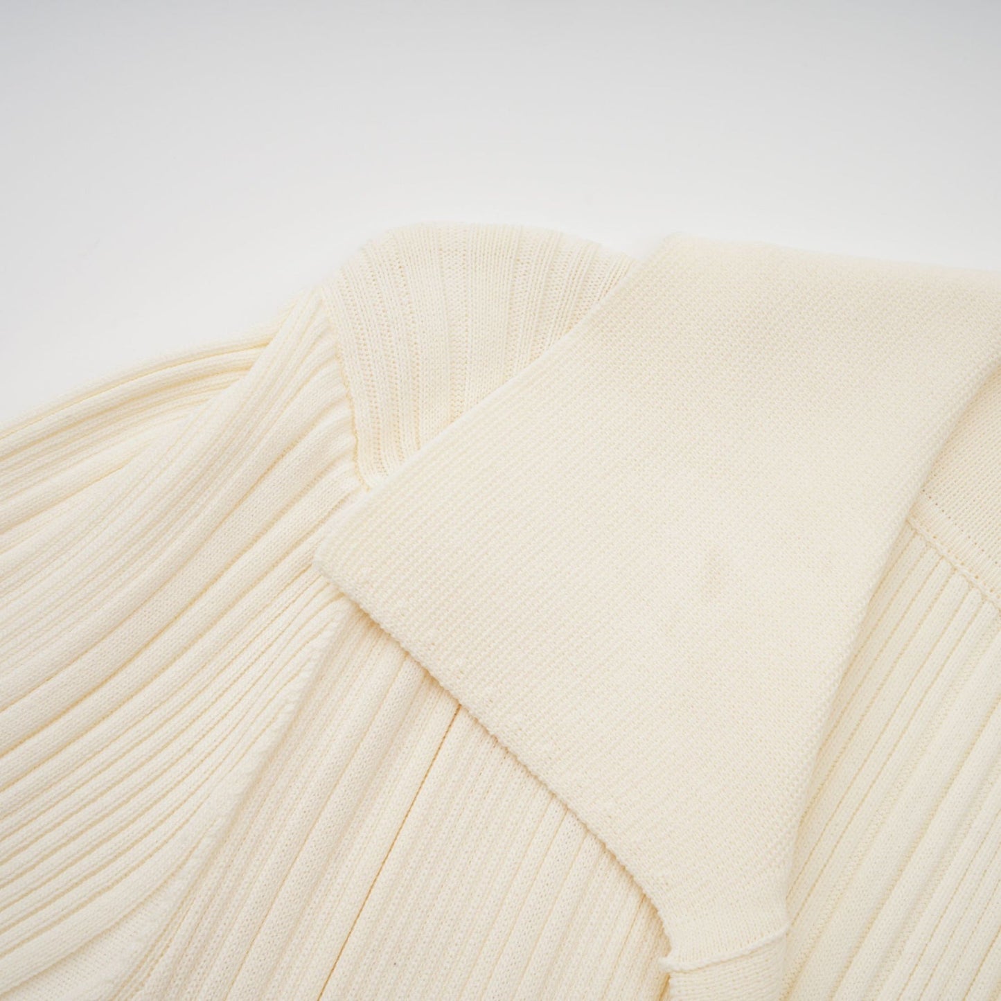 Woman wearing long sleeve ribbed knit midi dress in neutral color standing against plain background