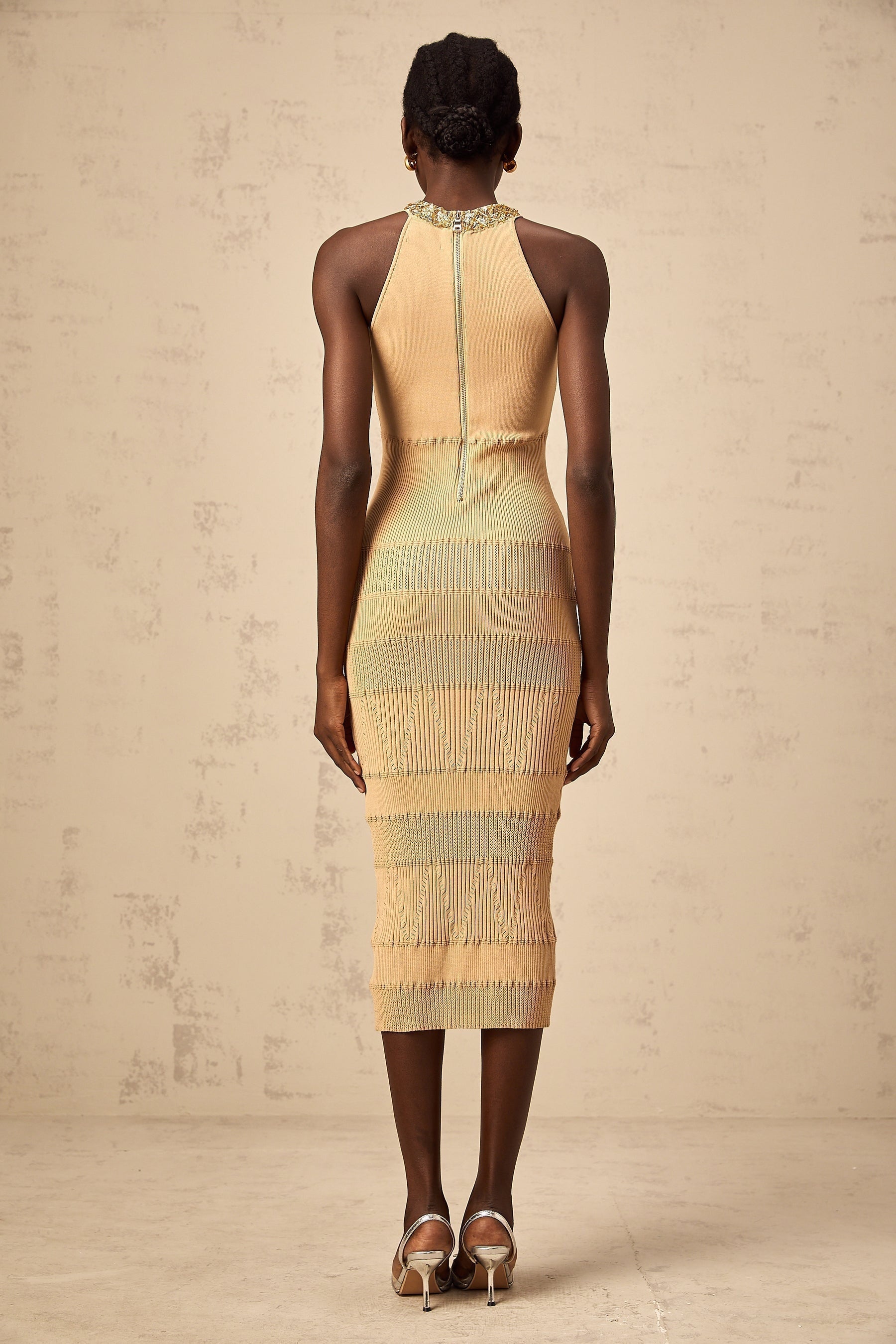 Woman wearing long sleeve sequined midi dress in ribbed knit fabric with sparkly finish and form fitting silhouette