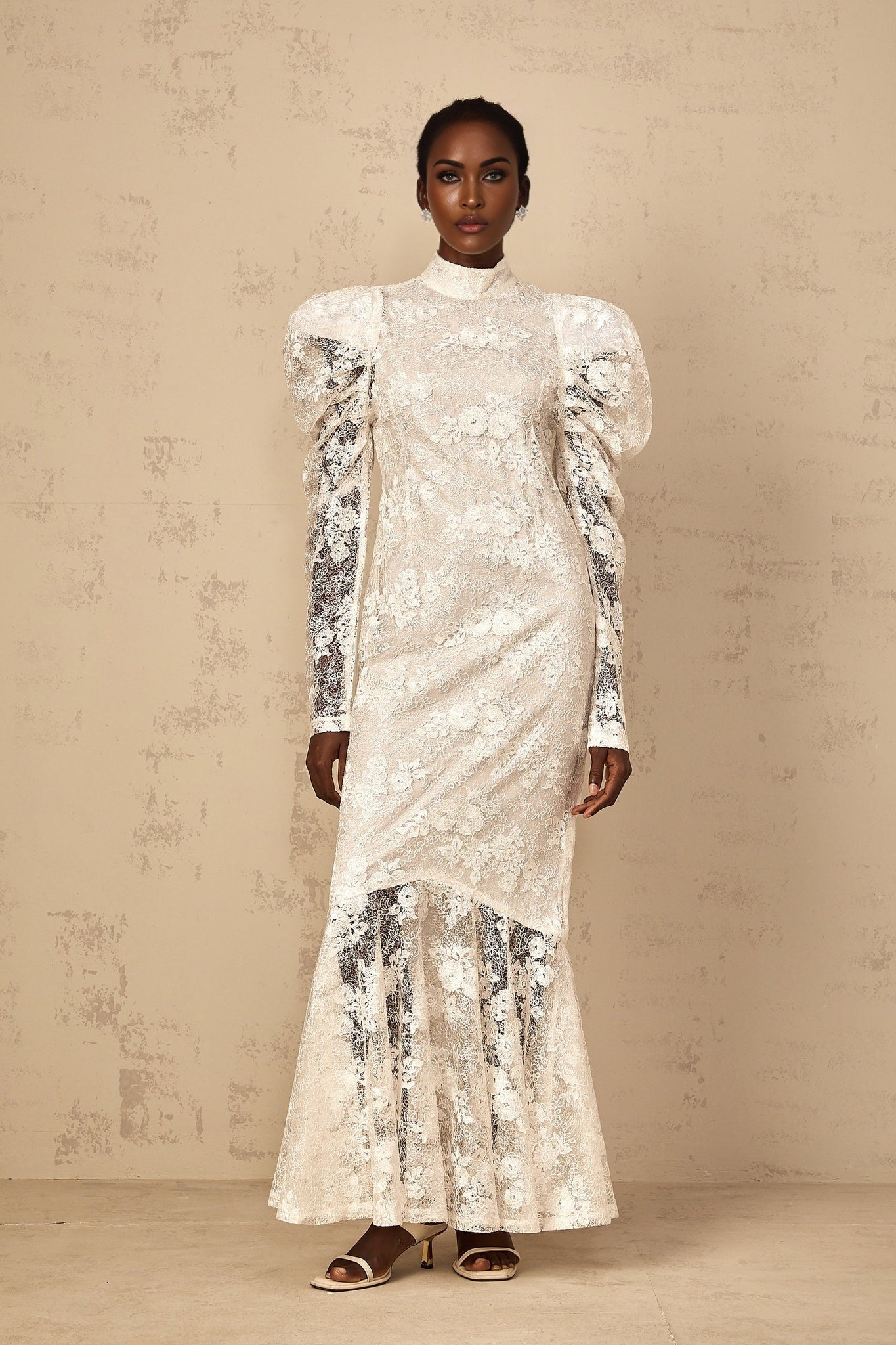 Woman wearing long white lace mermaid style dress with floral pattern and fitted silhouette