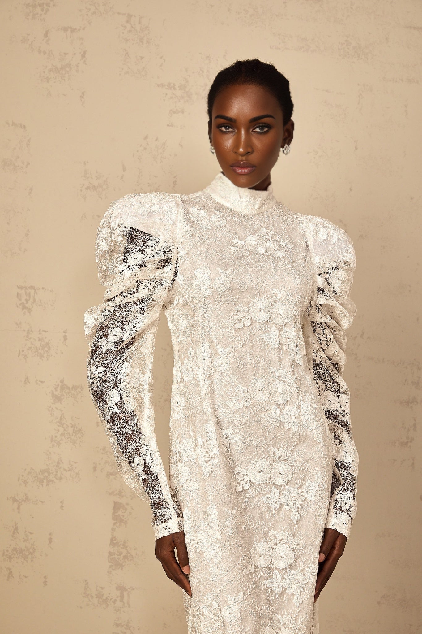 Woman wearing long white lace mermaid style dress with floral pattern and fitted silhouette