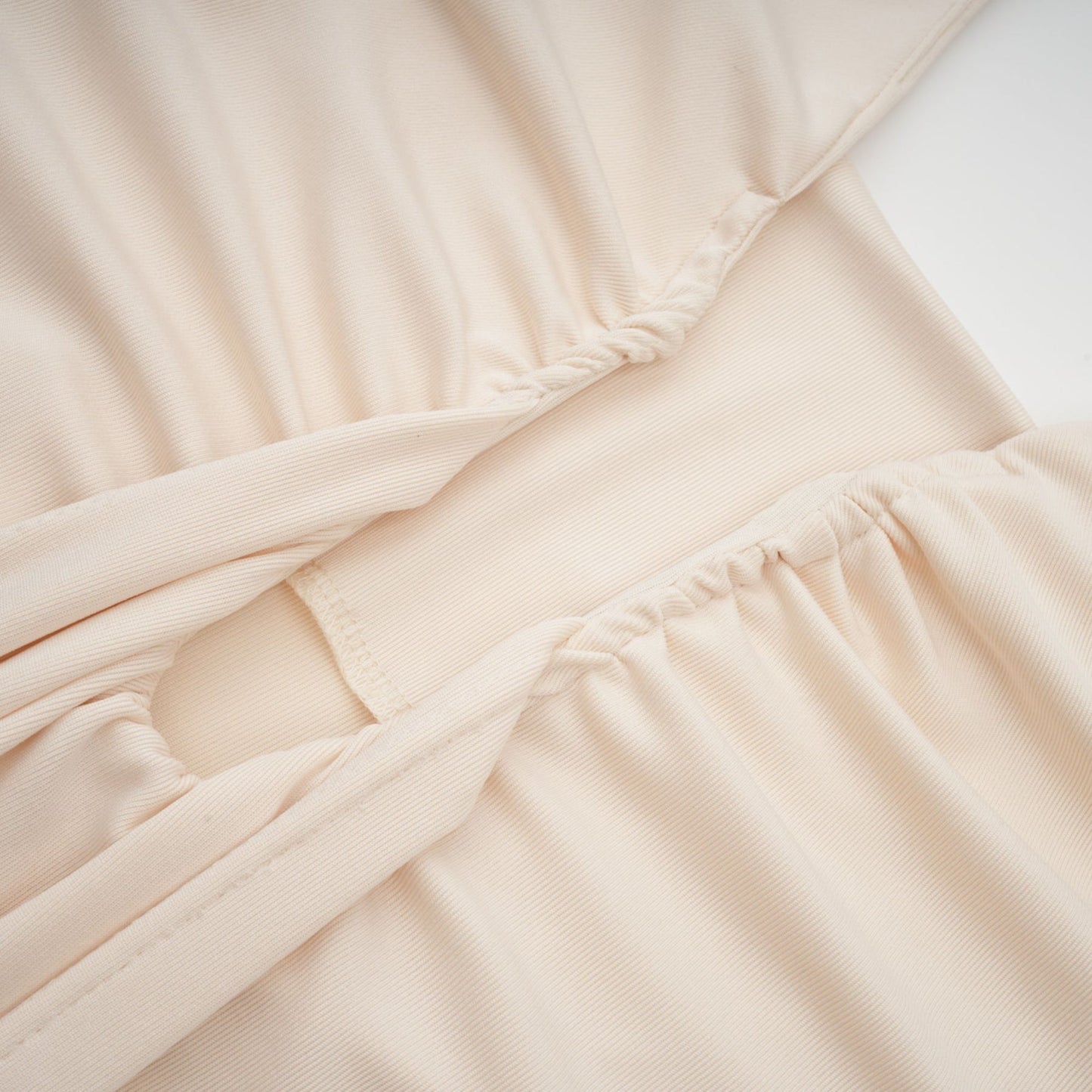 Woman wearing long white maxi dress with deep V neckline and draped design