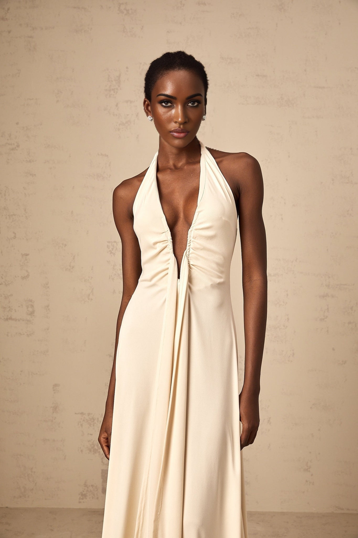 Woman wearing long white maxi dress with deep V neckline and draped detail