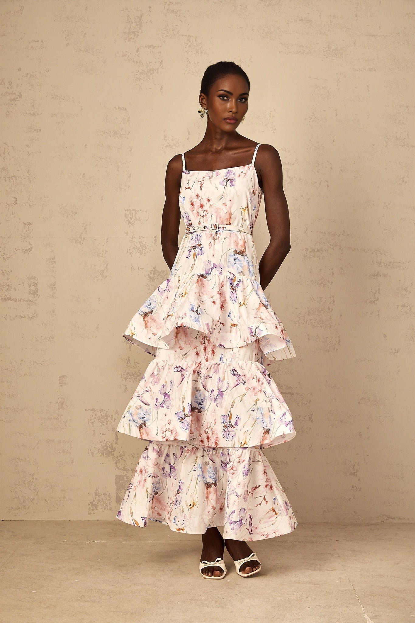 Woman wearing long white maxi dress with floral print and tiered ruffles