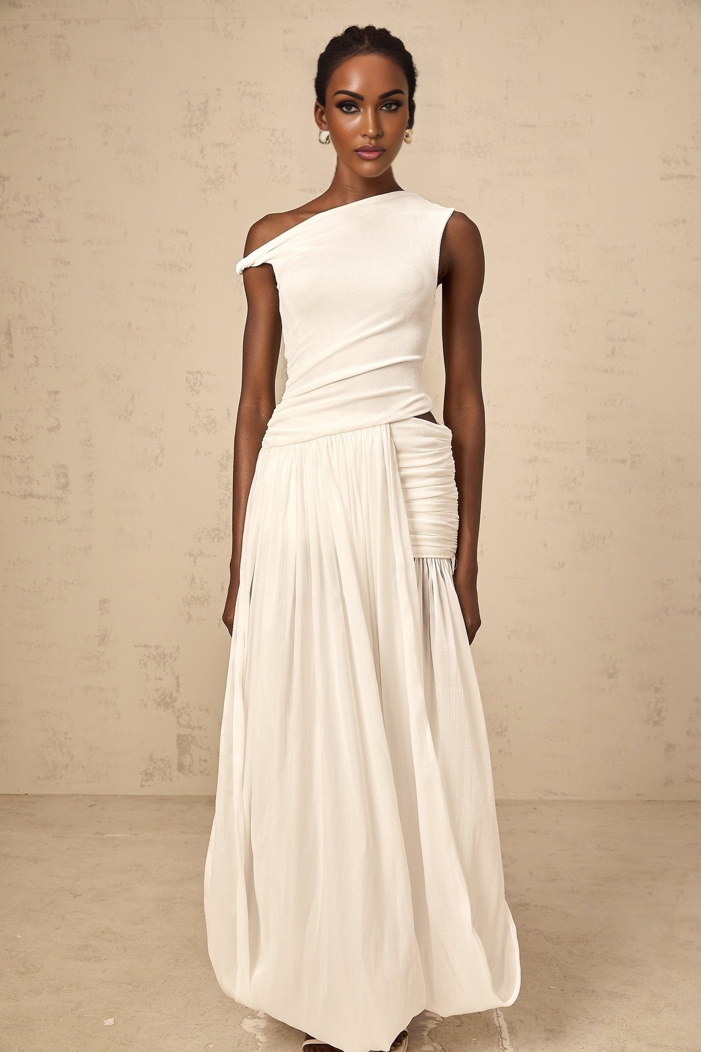 Woman wearing long white maxi dress with single shoulder strap and shirred panel detailing