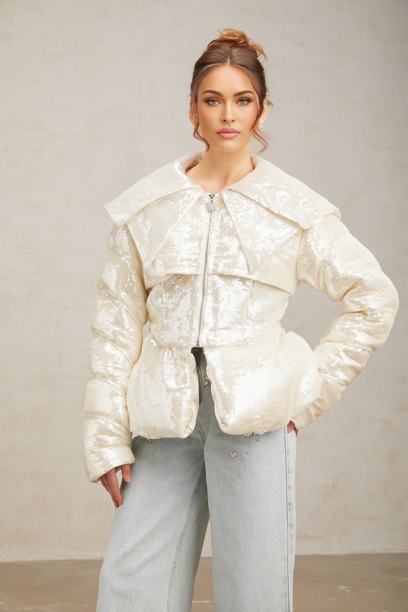 Woman wearing long white sequined down coat with hood and zipper closure