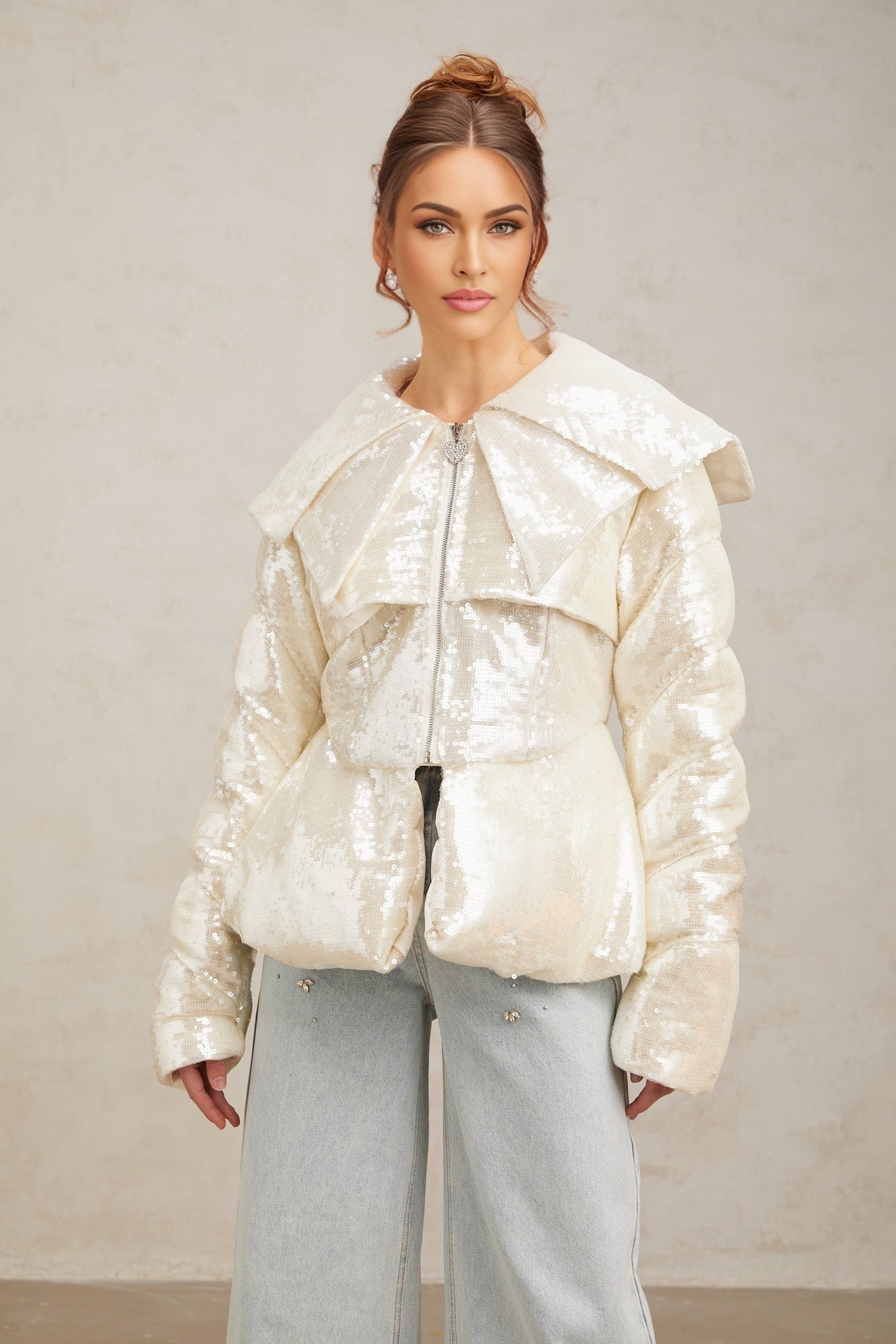 Woman wearing long white winter coat with sequin embellishments and down filling