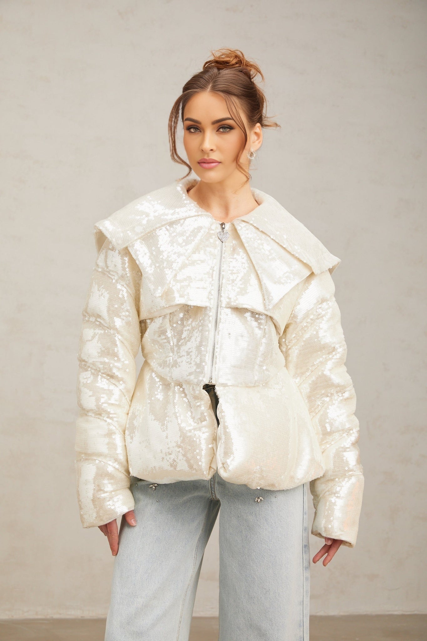 Woman wearing long white winter coat with shiny sequin embellishments and puffy down insulation