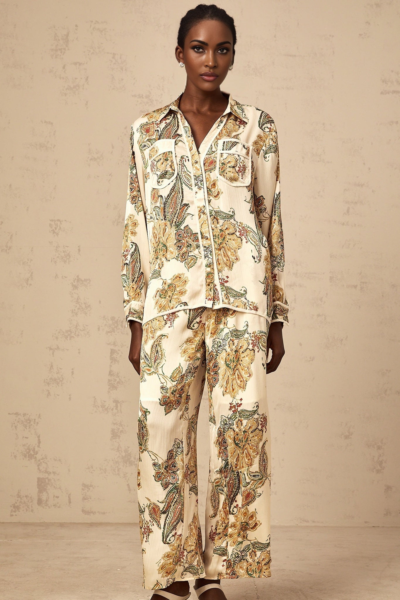 Woman wearing matching beige floral print shirt and trousers set with loose fit and neutral tones