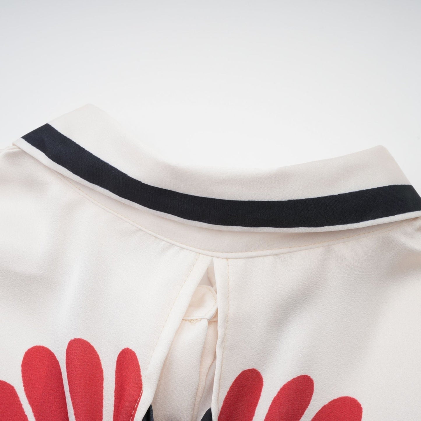 Woman wearing matching floral print shirt and trousers set in vibrant colors standing against plain background