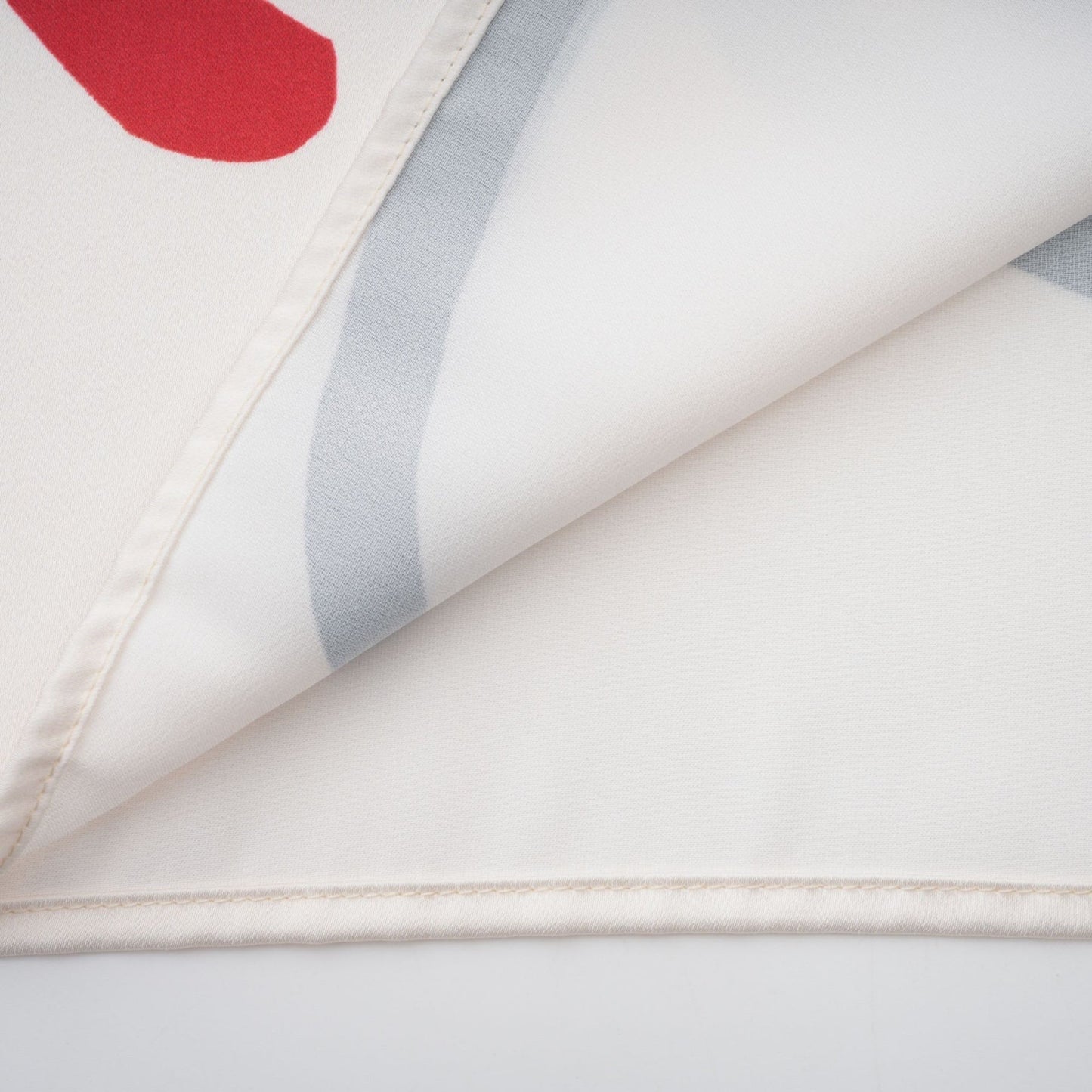 Woman wearing matching graphic print shirt and trousers in vibrant colors with floral or tropical patterns standing against plain background