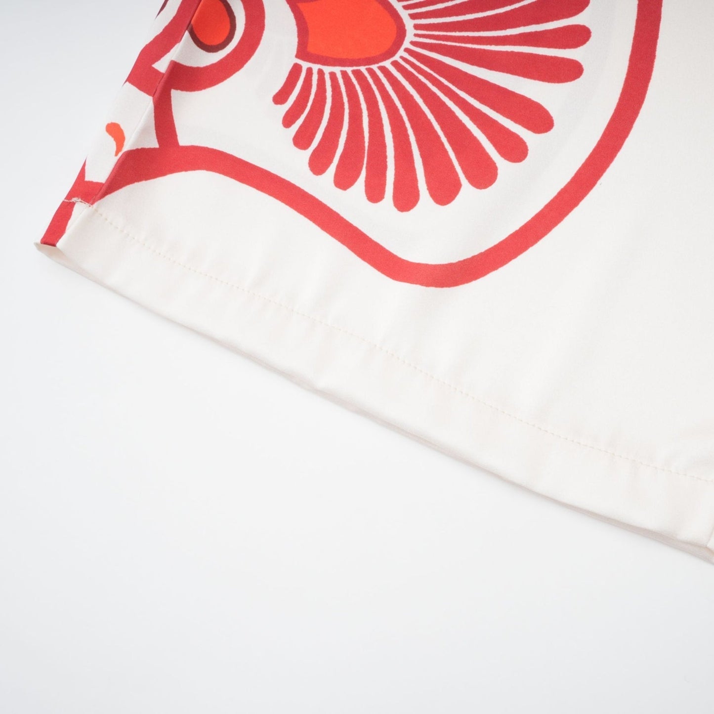 Woman wearing matching graphic print shirt and trousers set with vibrant floral pattern in bright colors against white background