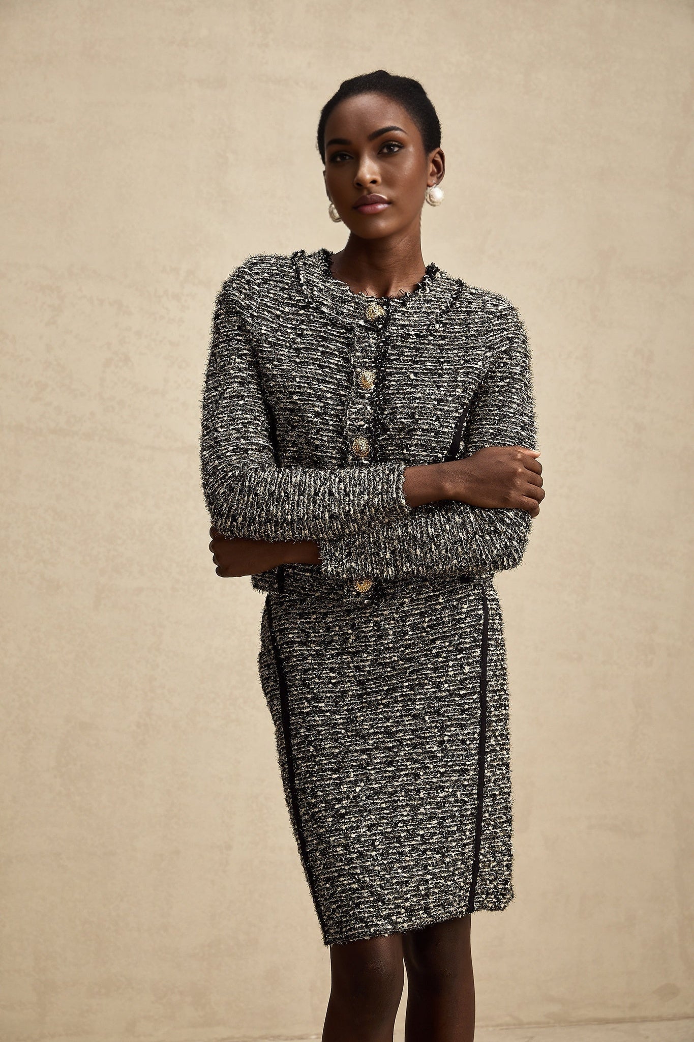 Woman wearing matching jacket and skirt set in contrasting colors with shimmering lurex fabric details