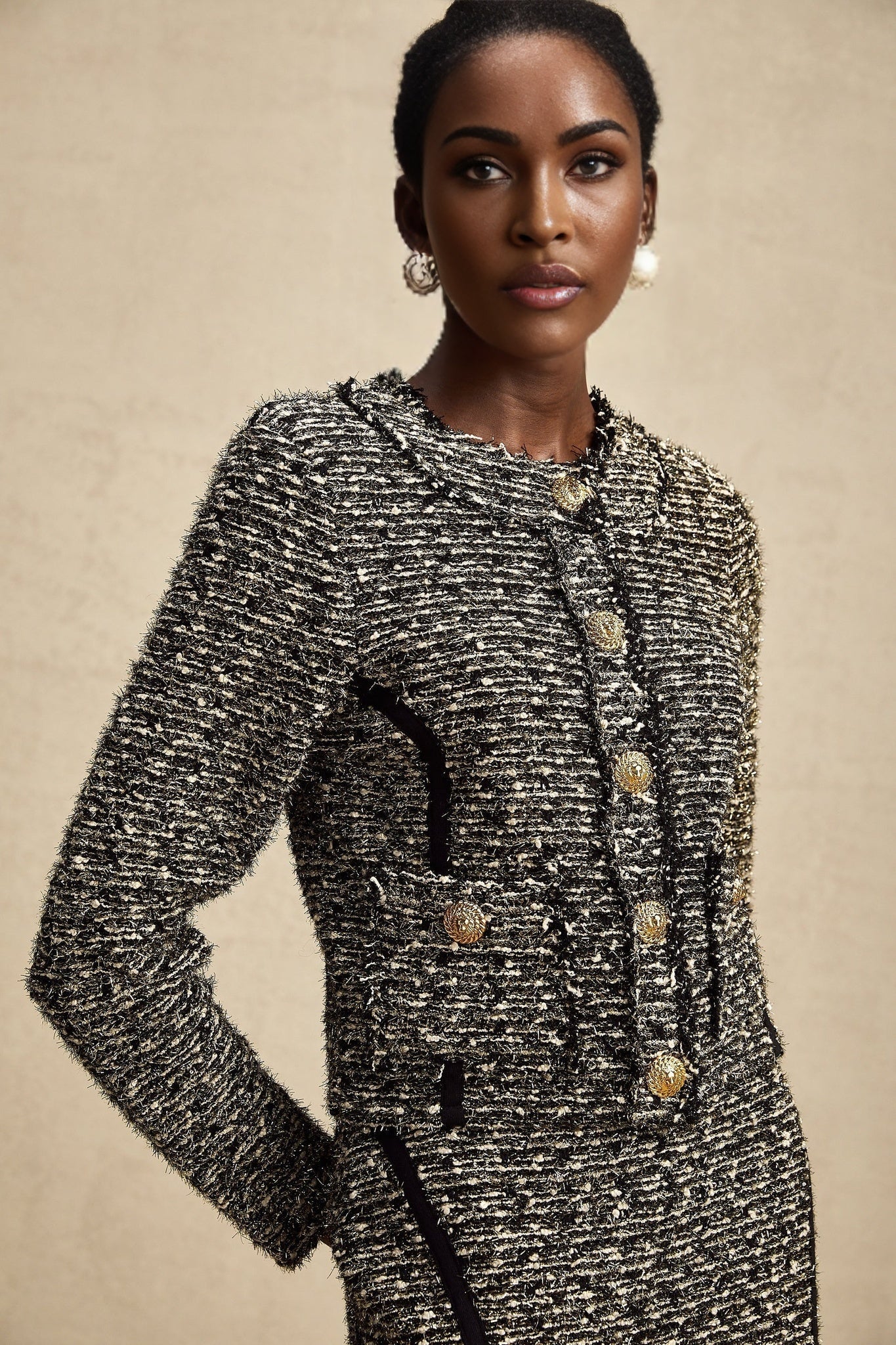 Woman wearing matching silver lurex jacket and skirt set with contrasting black trim and details