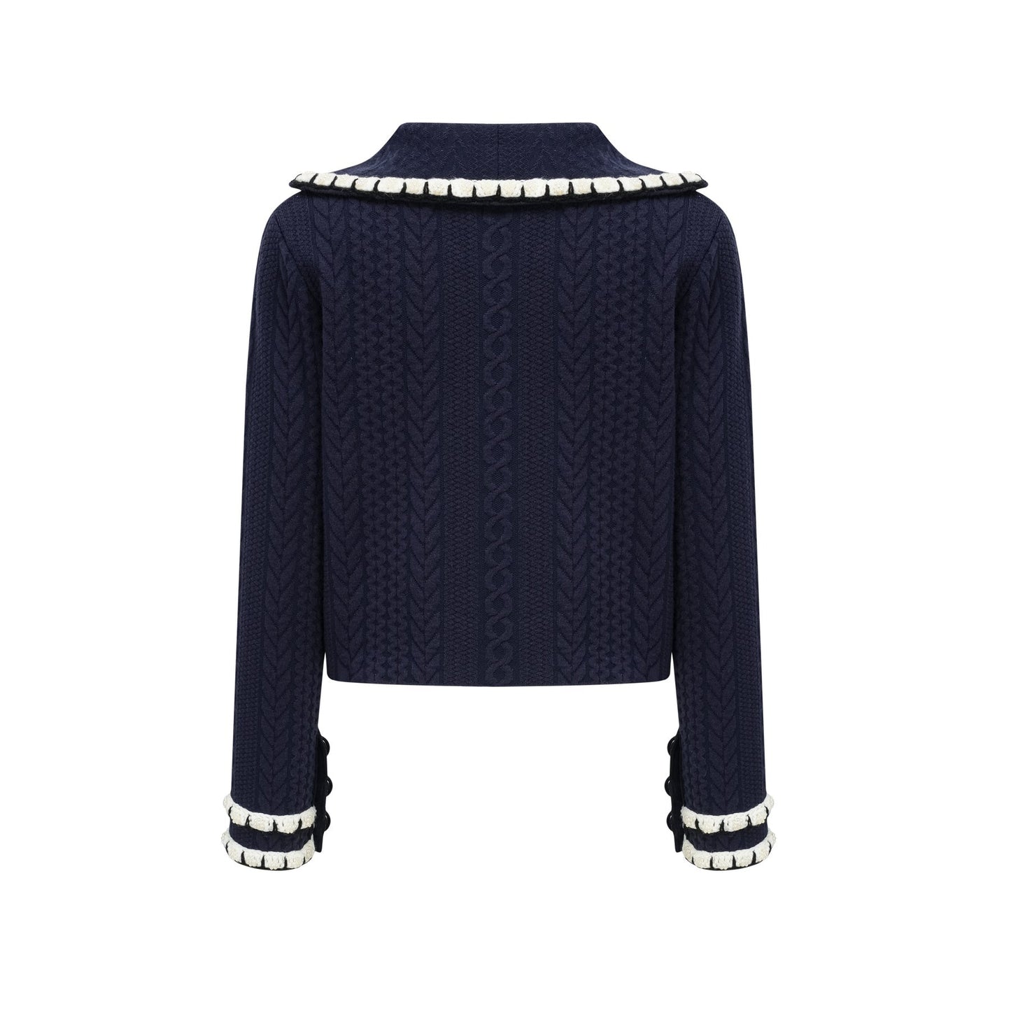 Woman wearing navy blue crochet knit cardigan and matching trousers standing against plain background