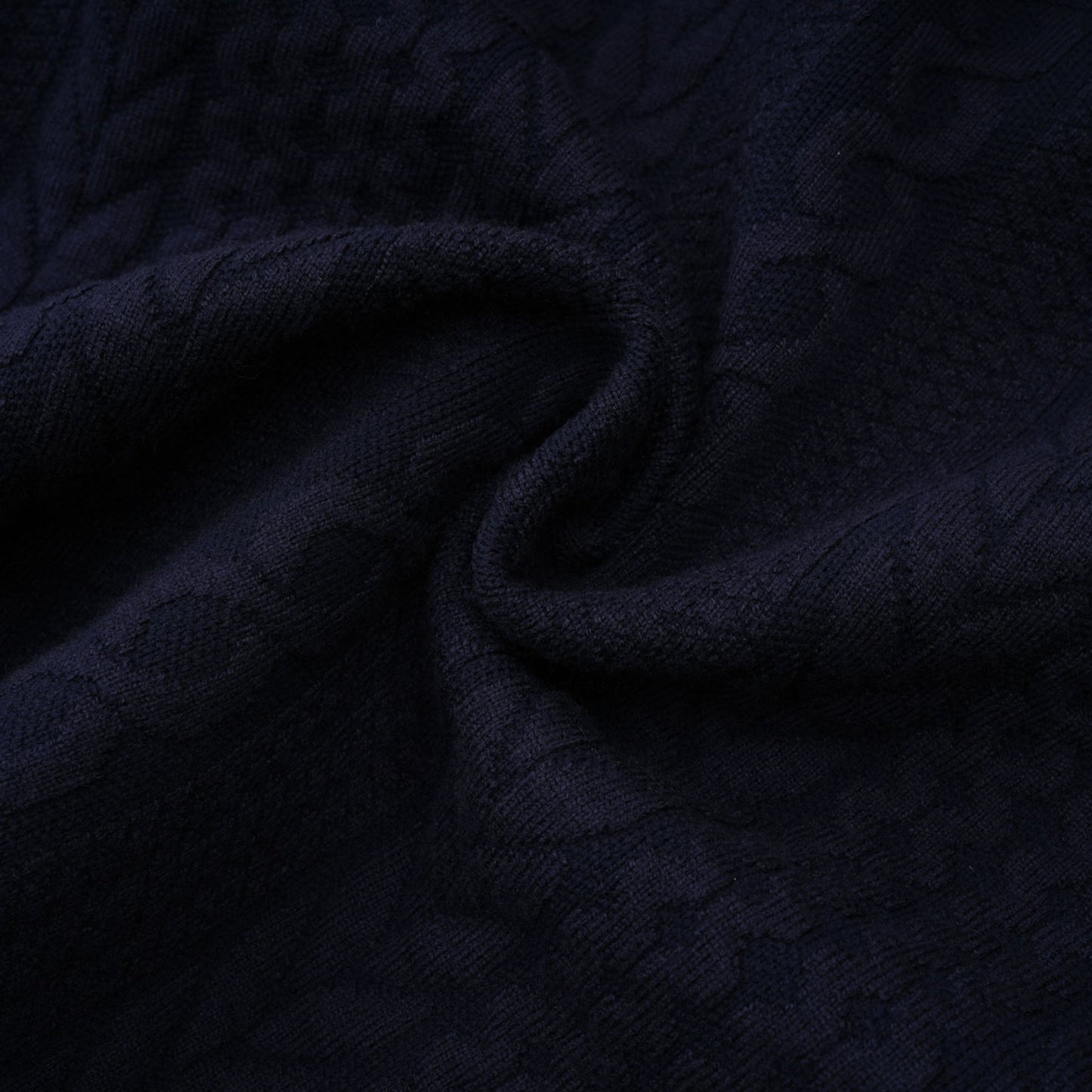 Woman wearing navy blue crochet knit cardigan and matching trousers standing against plain background