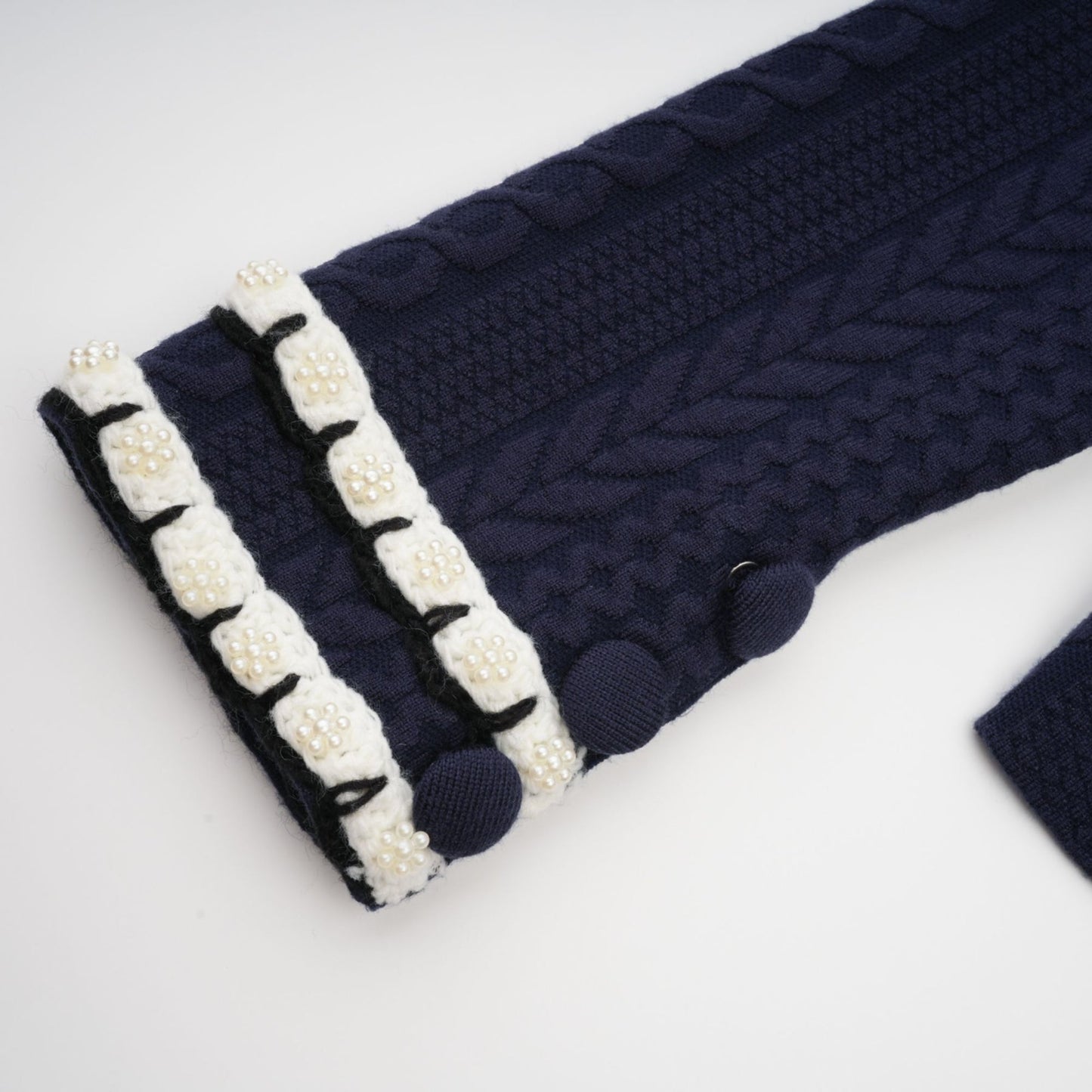 Woman wearing navy blue crochet knit cardigan and matching trousers standing in relaxed pose