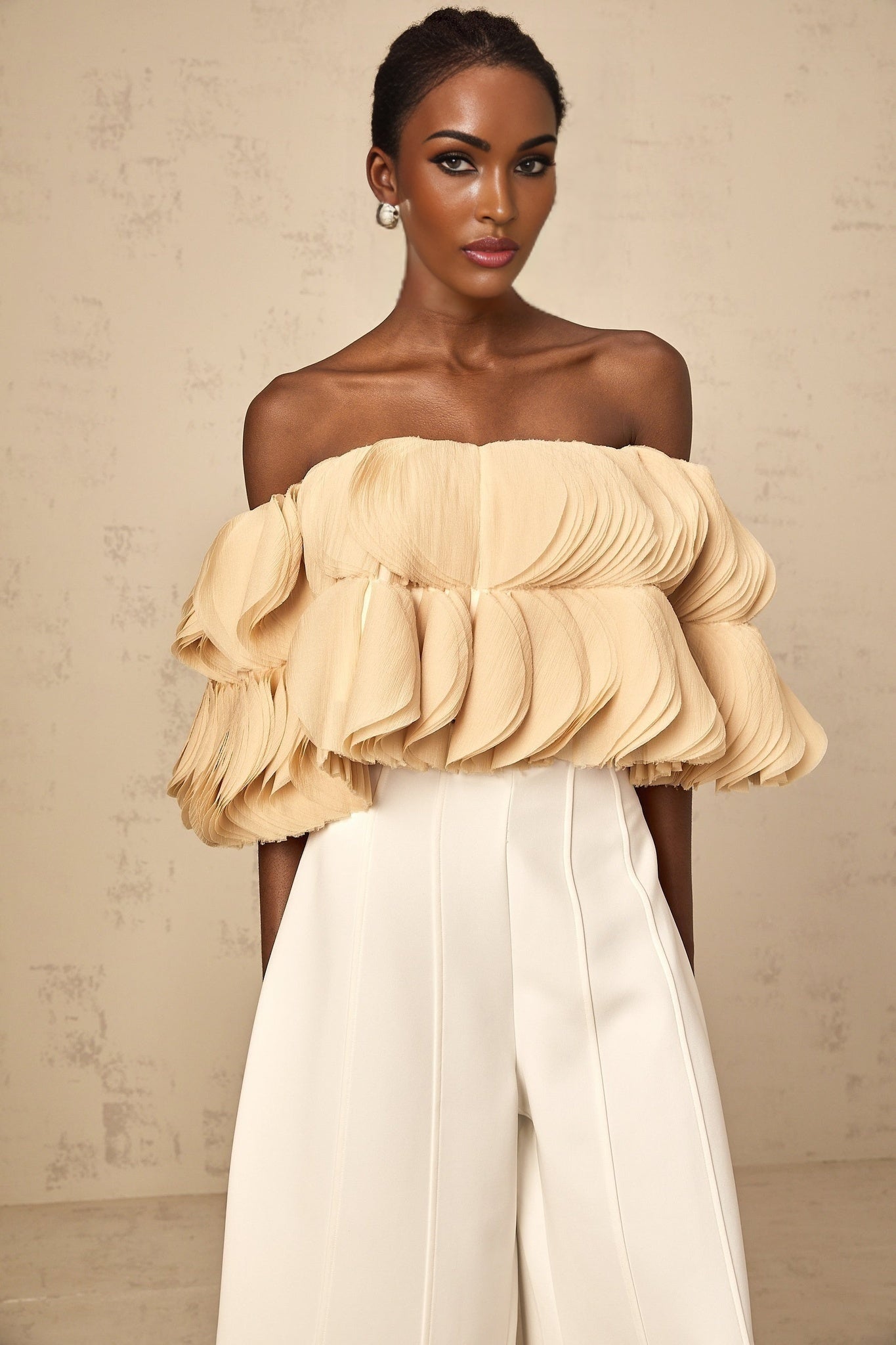 Woman wearing neutral colored off shoulder cropped top with shirred fabric detail