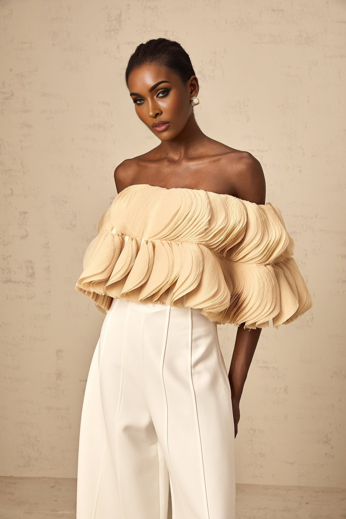 Woman wearing neutral colored offshoulder cropped top with shirred detailing