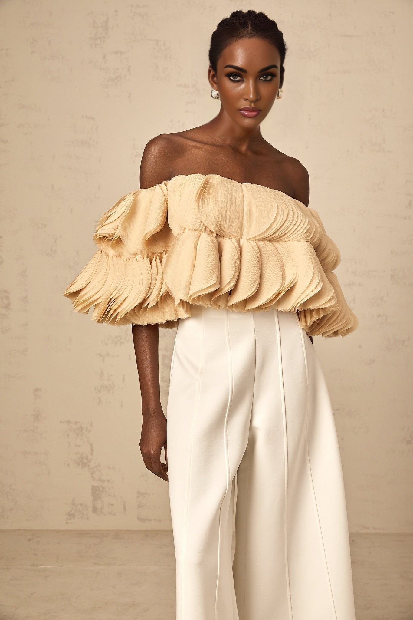 Woman wearing neutral colored offshoulder cropped top with shirred detailing