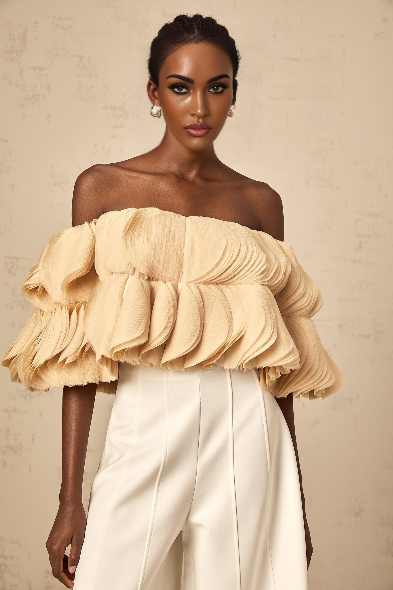Woman wearing neutral colored offshoulder cropped top with shirred fabric detail