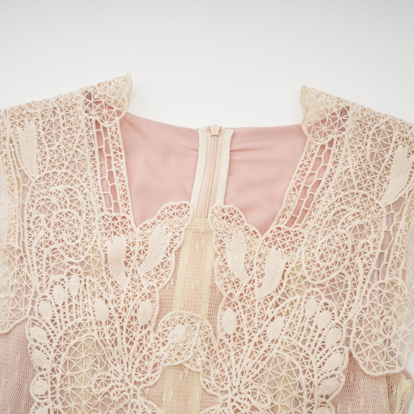 Woman wearing neutral colored tulle midi dress with floral lace panelling and sleeveless design