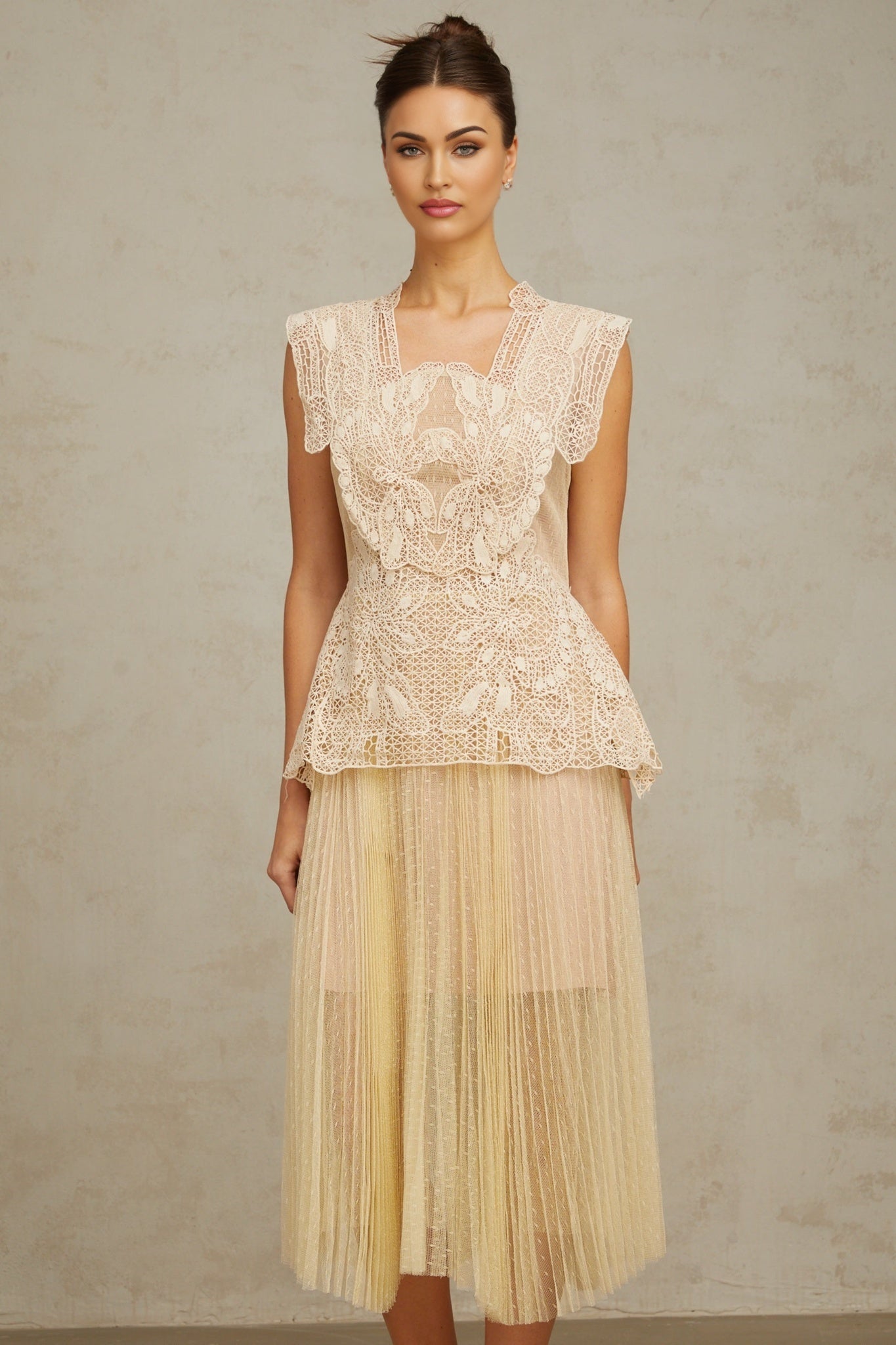 Woman wearing neutral colored tulle midi dress with floral lace panels delicate straps and flowing skirt
