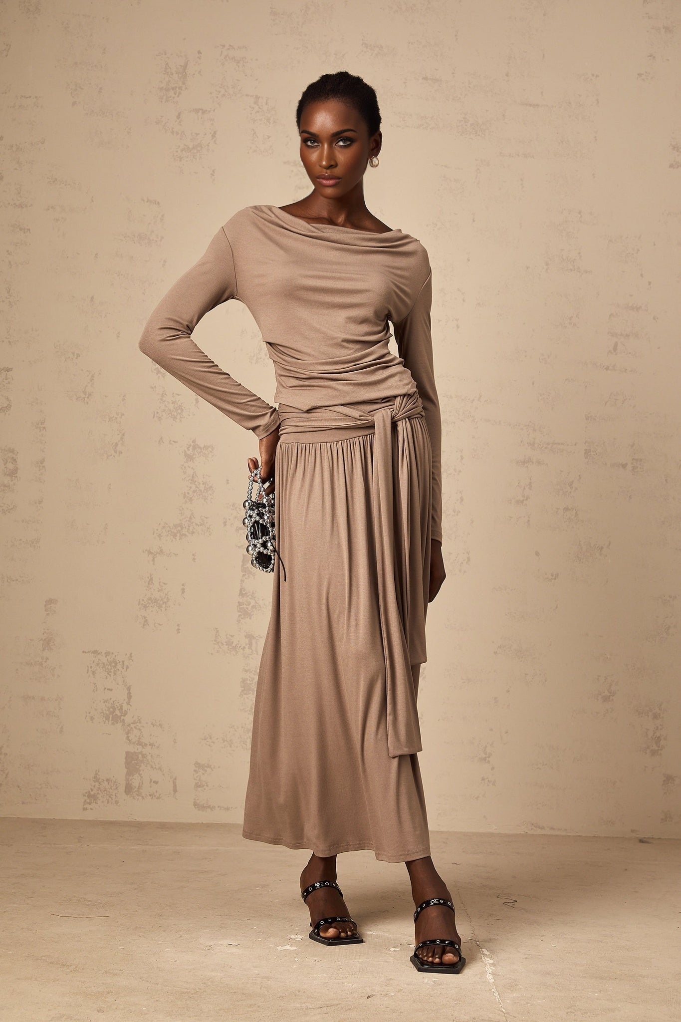 Woman wearing oatmeal colored matching set with draped top and fitted skirt