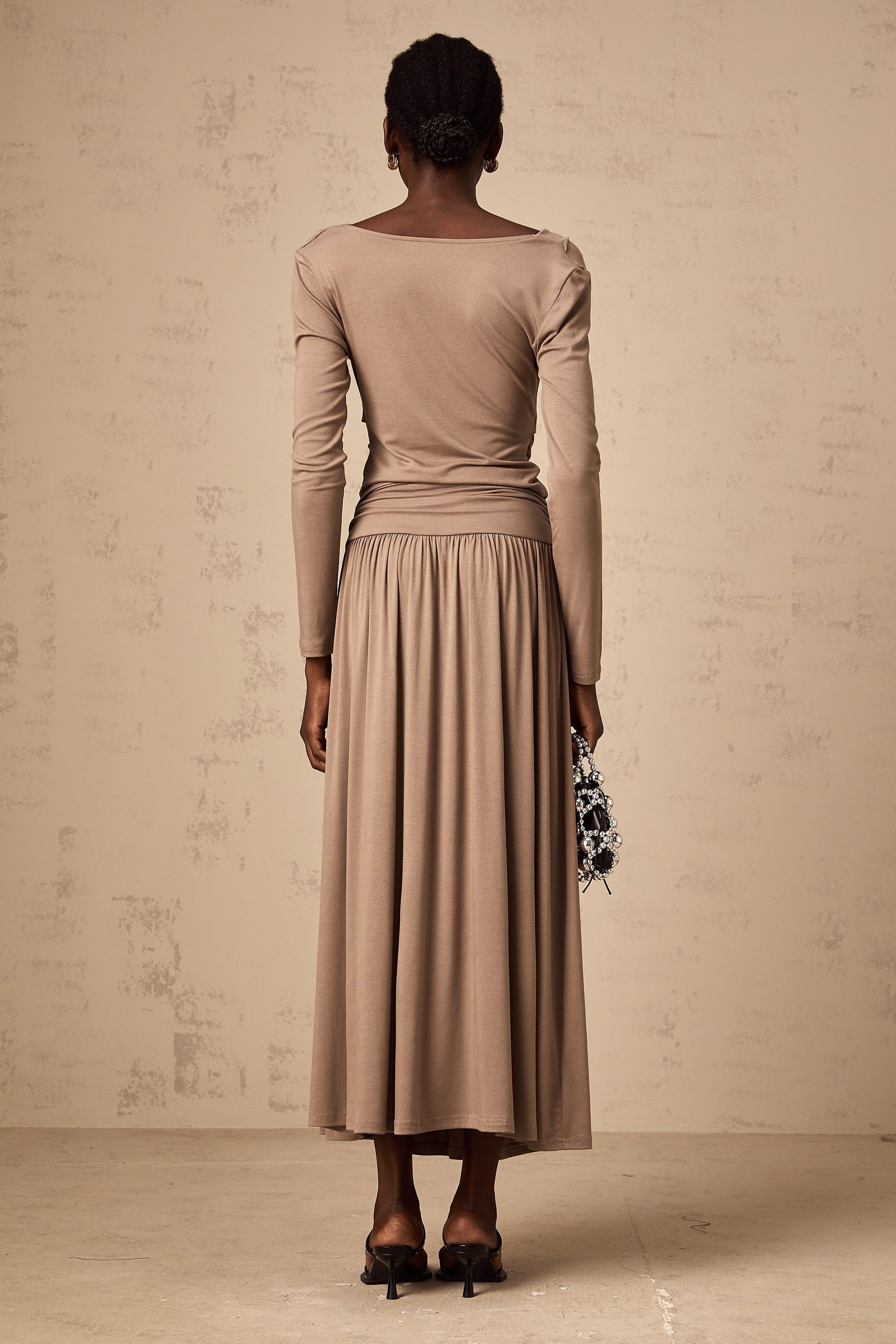 Woman wearing oatmeal colored matching set with draped top and fitted skirt