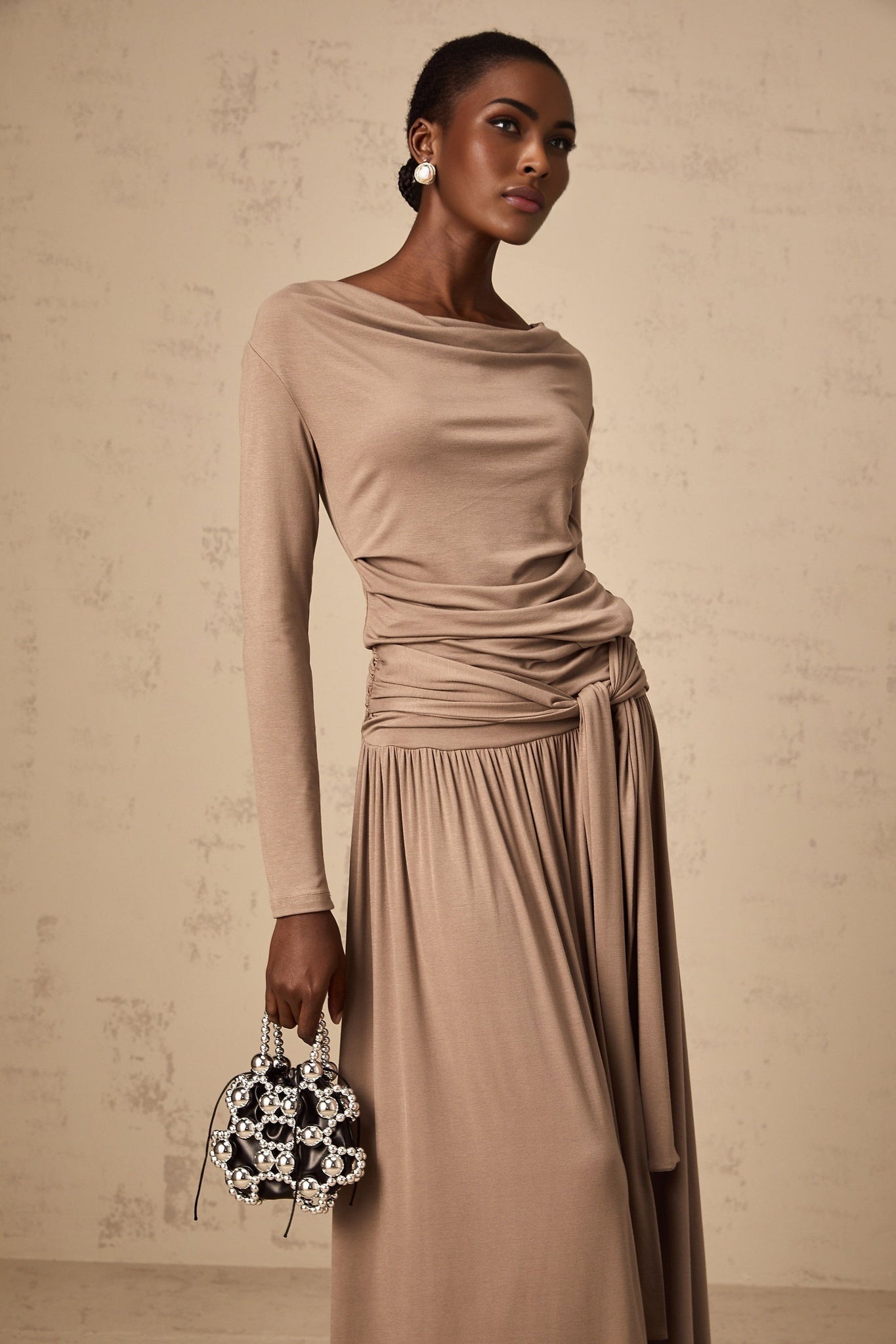 Woman wearing oatmeal colored matching set with draped top and fitted skirt