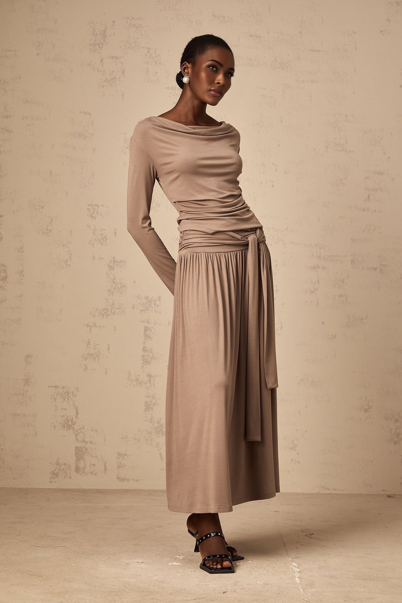 Woman wearing oatmeal colored matching set with draped top and skirt made of stretchy fabric