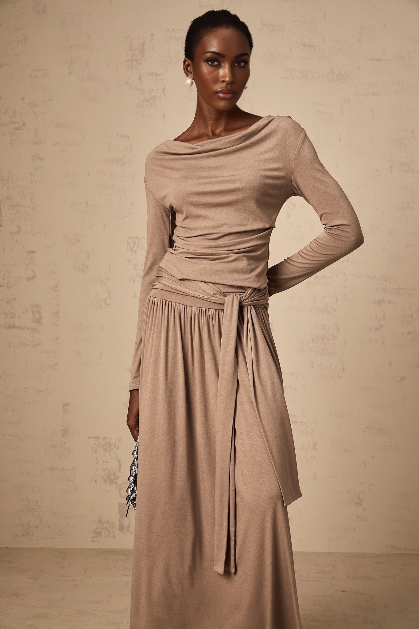 Woman wearing oatmeal colored matching set with draped top and skirt made of stretchy fabric