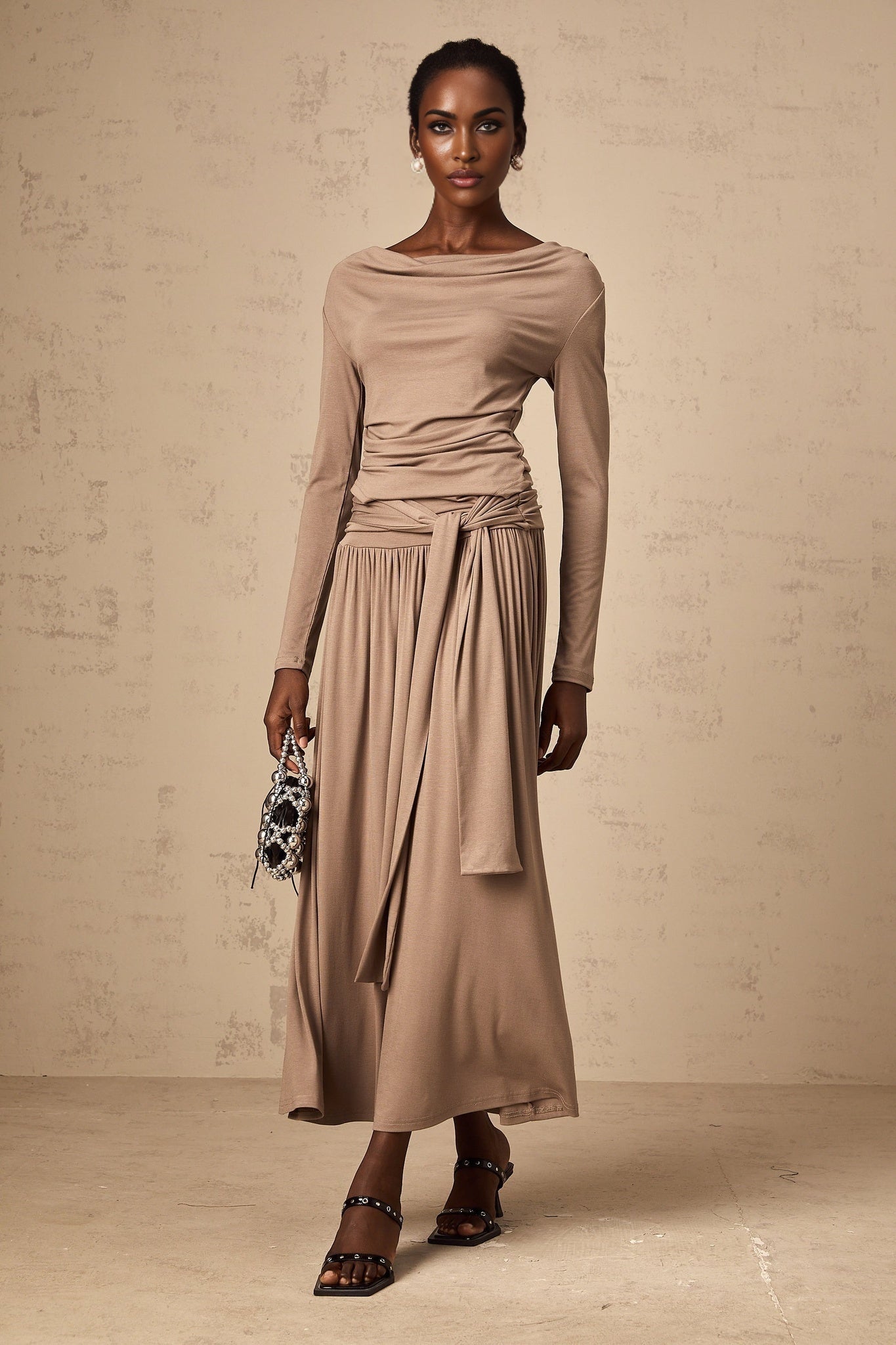 Woman wearing oatmeal colored matching set with draped top and skirt made of stretchy fabric