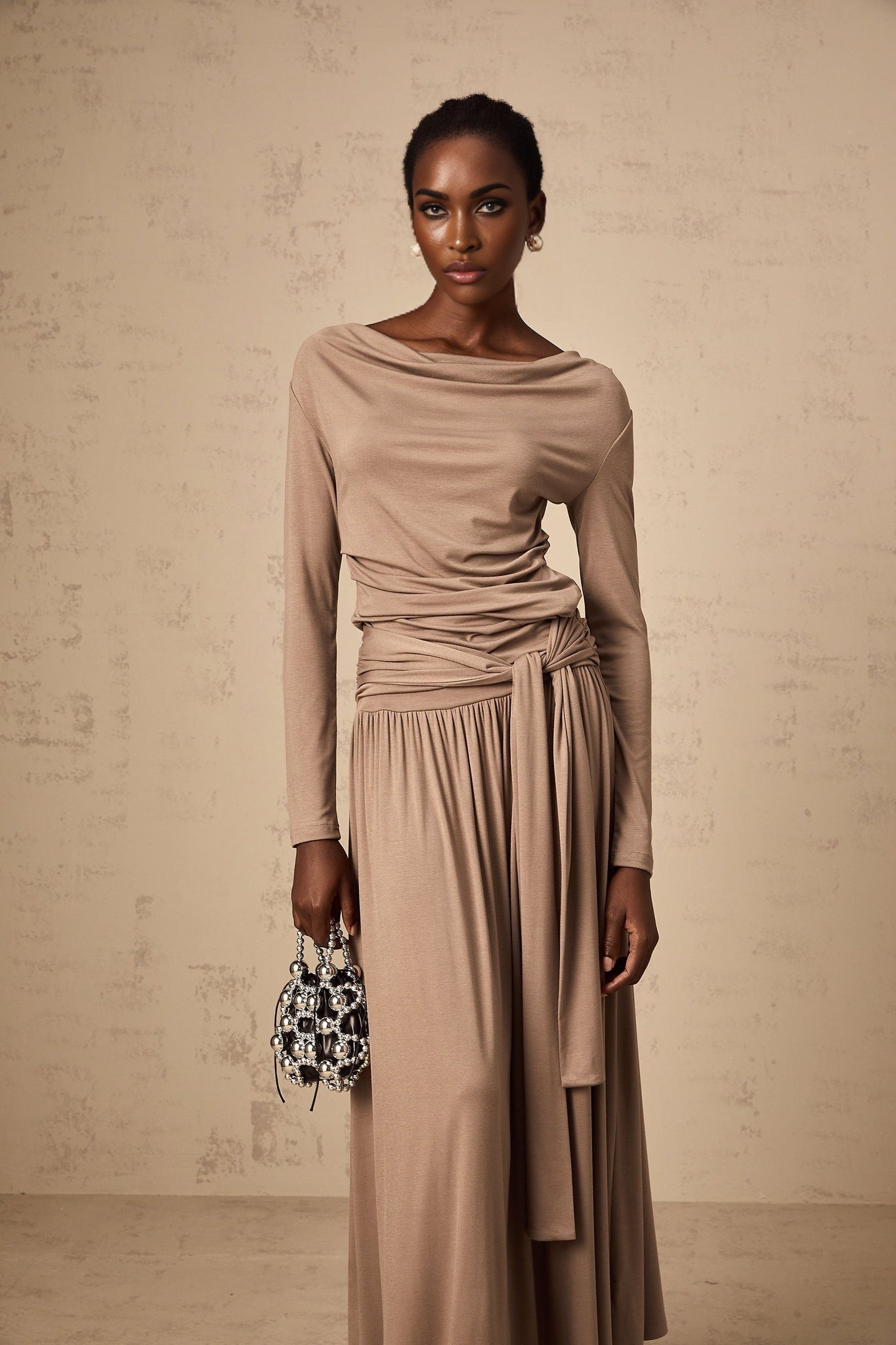 Woman wearing oatmeal colored matching set with draped top and skirt made of stretchy fabric