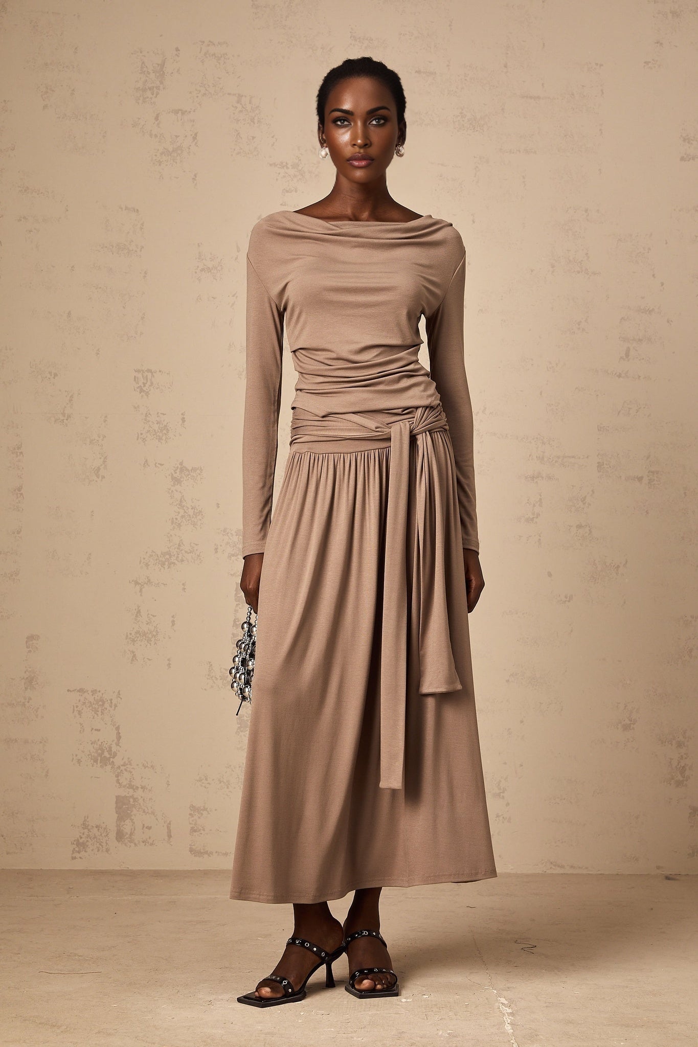 Woman wearing oatmeal colored matching set with draped top and skirt made of stretchy fabric