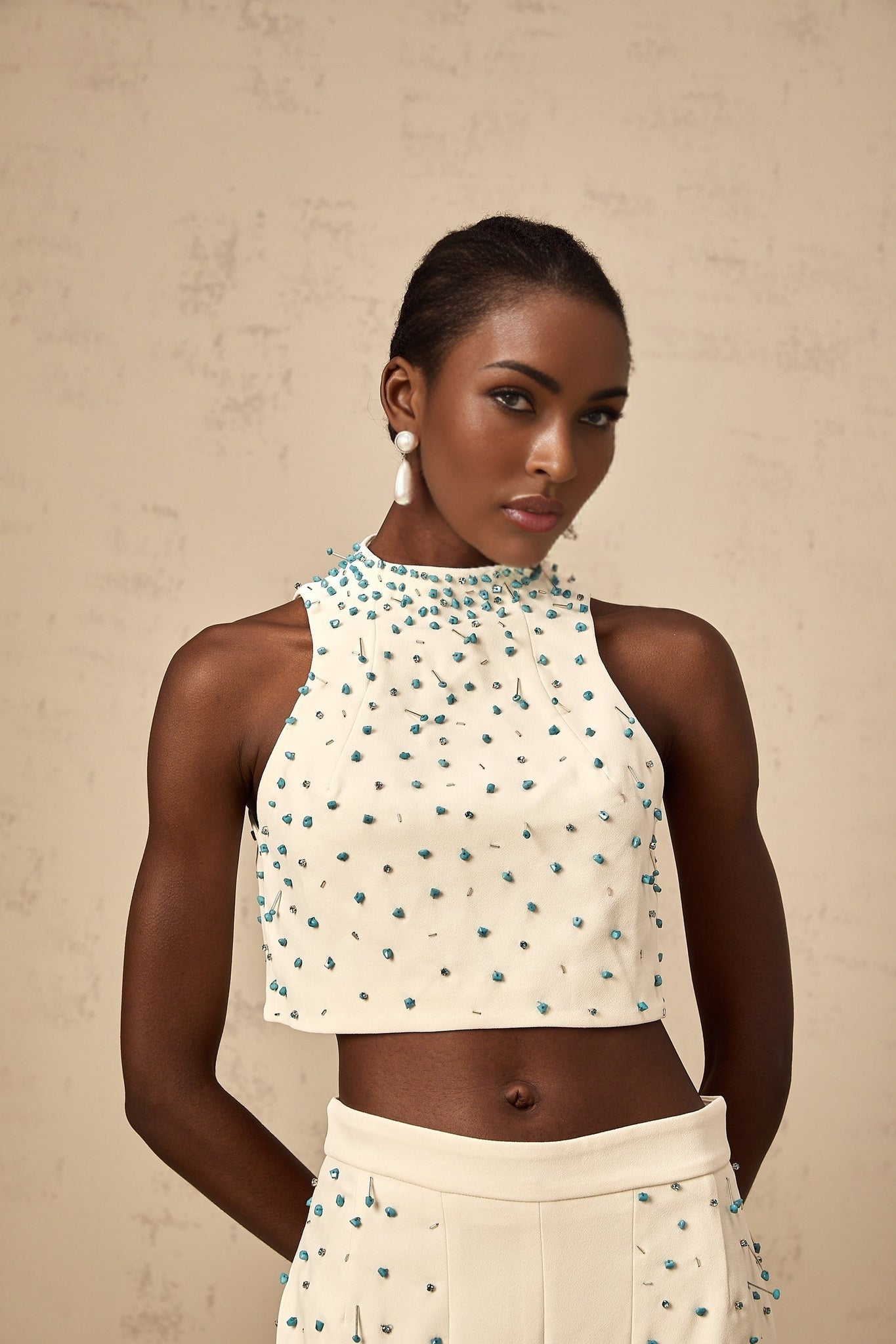 Woman wearing offwhite matching set with embellished top and skirt called Clothilde