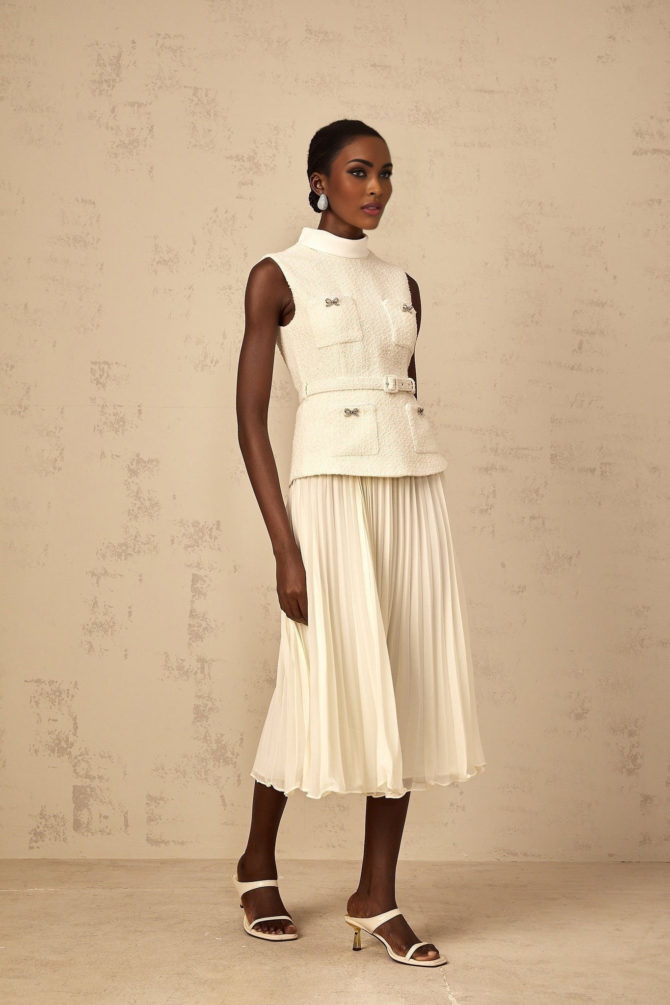 Woman wearing offwhite midi dress with tweed bodice and tulle skirt panel standing against plain background