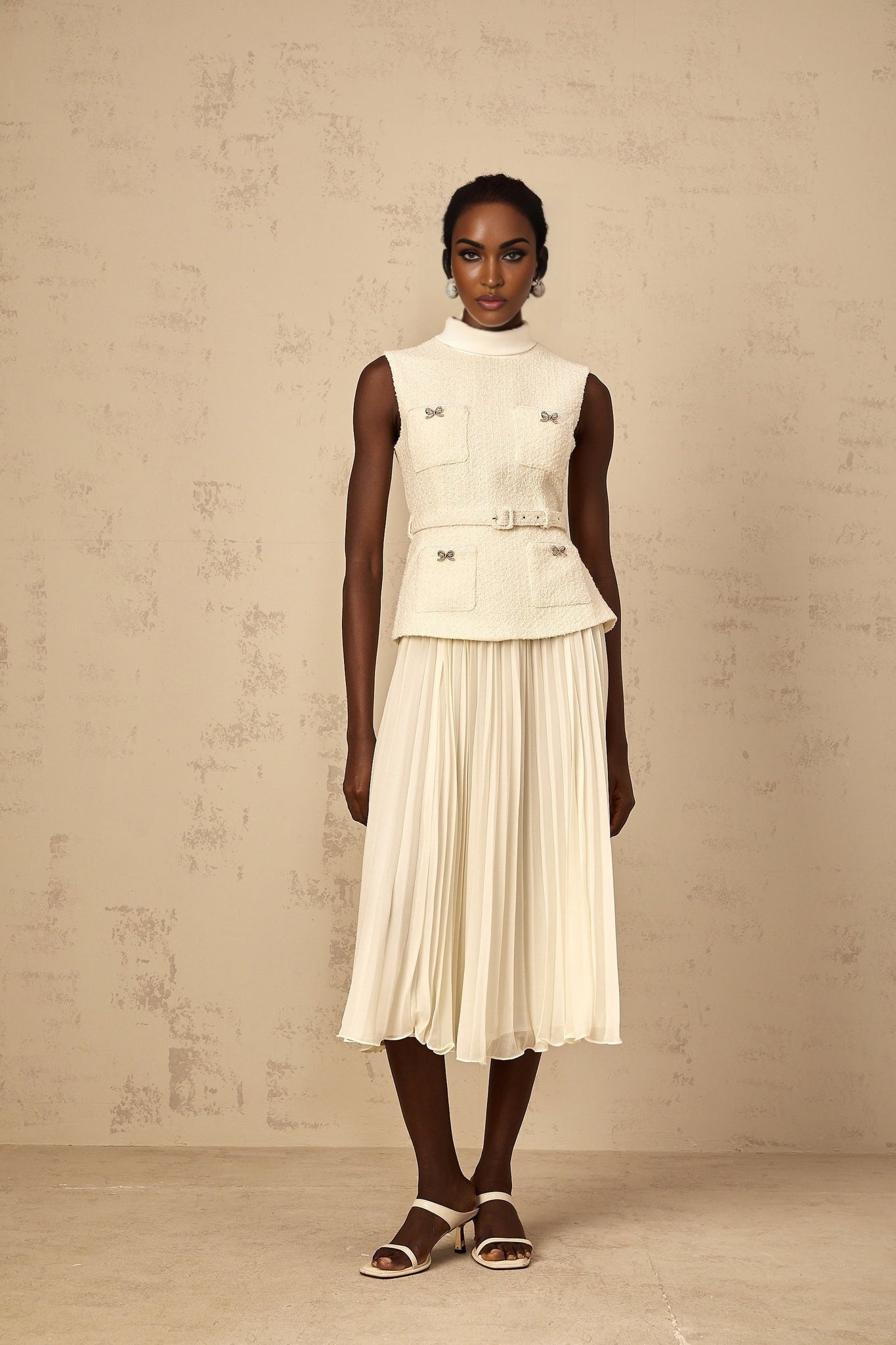 Woman wearing offwhite tweed midi dress with tulle panel detailing and long sleeves standing in front of plain background