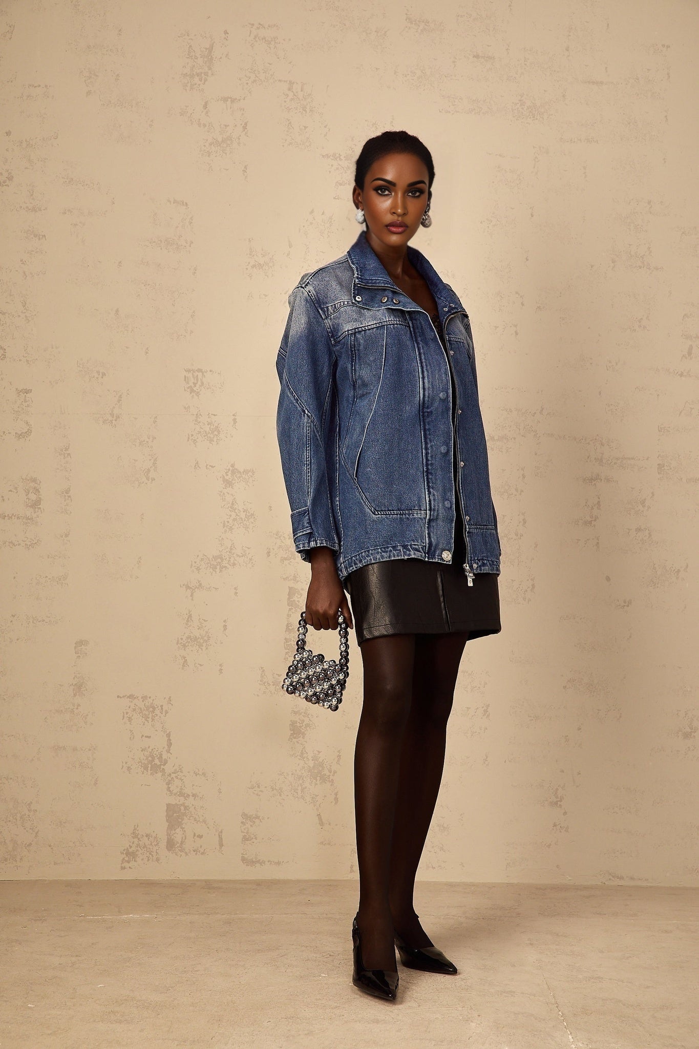 Woman wearing oversized blue denim jacket with patchwork design and loose fit