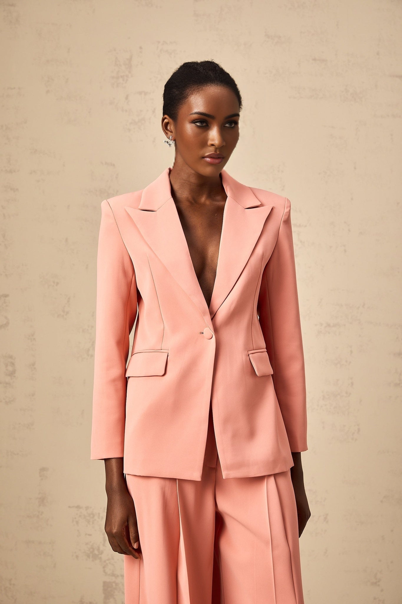 Woman wearing pink blazer and trousers set with embroidery details and cutout design