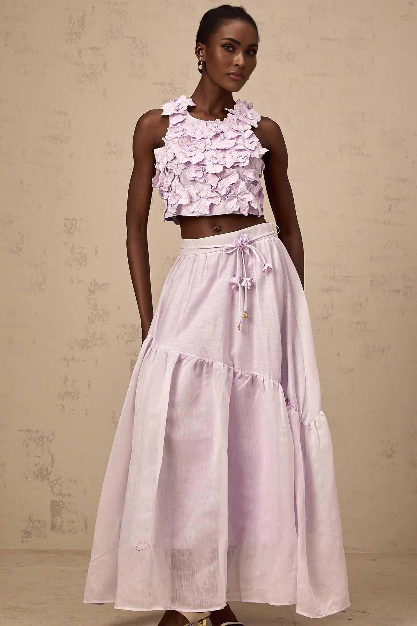 Woman wearing purple floral print matching top and skirt set with faux flowers