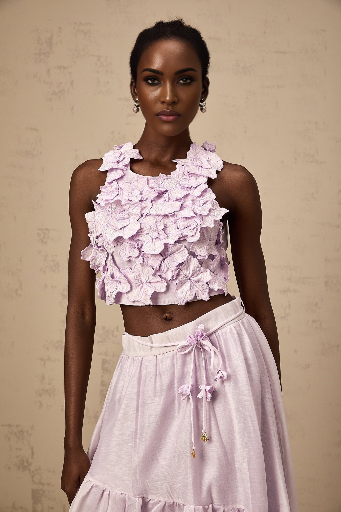 Woman wearing purple floral print top and matching skirt set with faux flower design