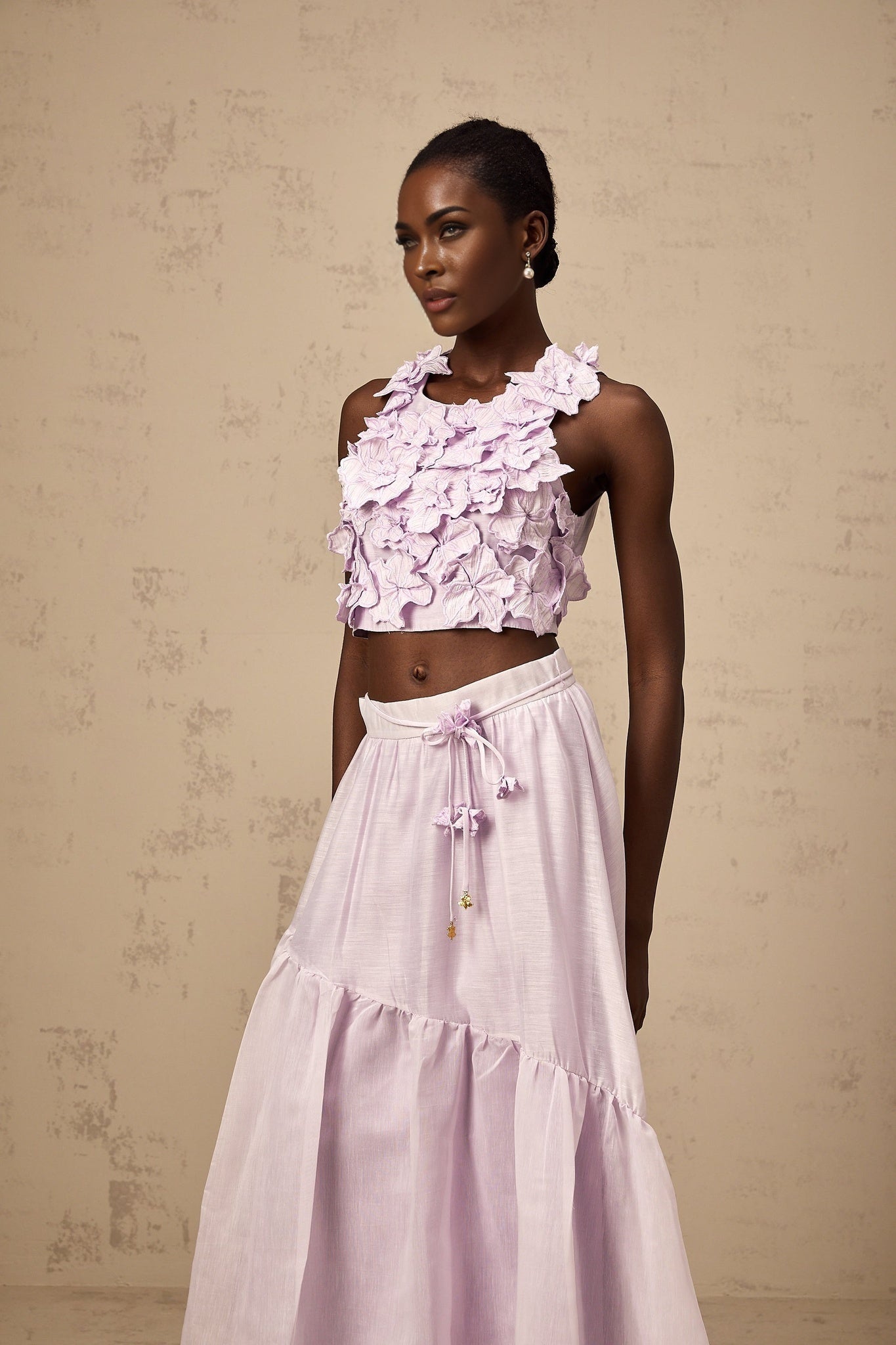 Woman wearing purple floral top and matching skirt set with faux flowers