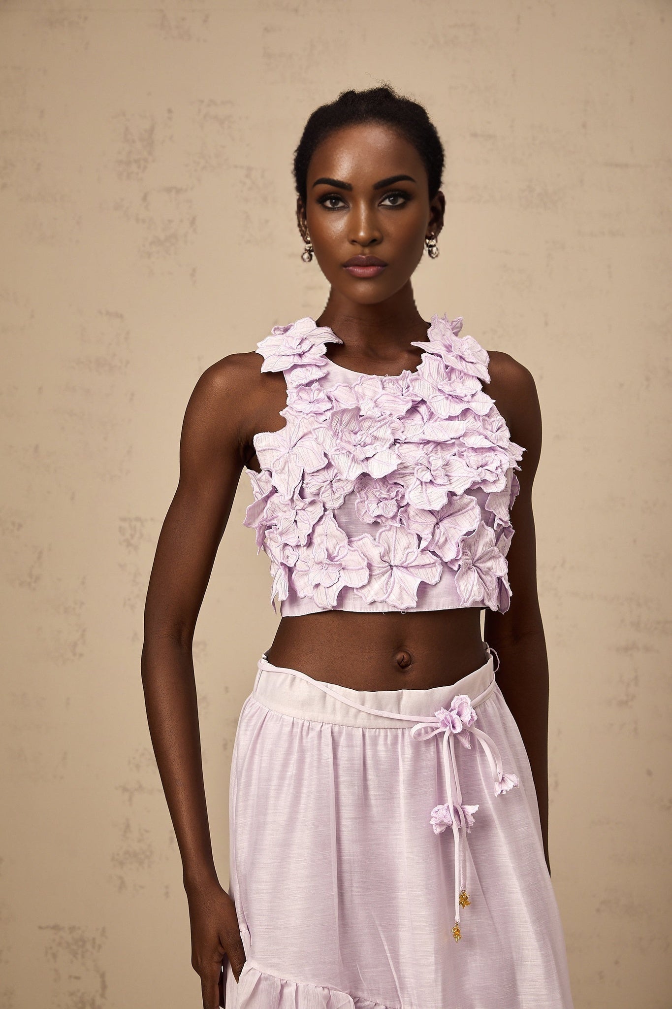 Woman wearing purple matching set with floral top and skirt made of faux flowers