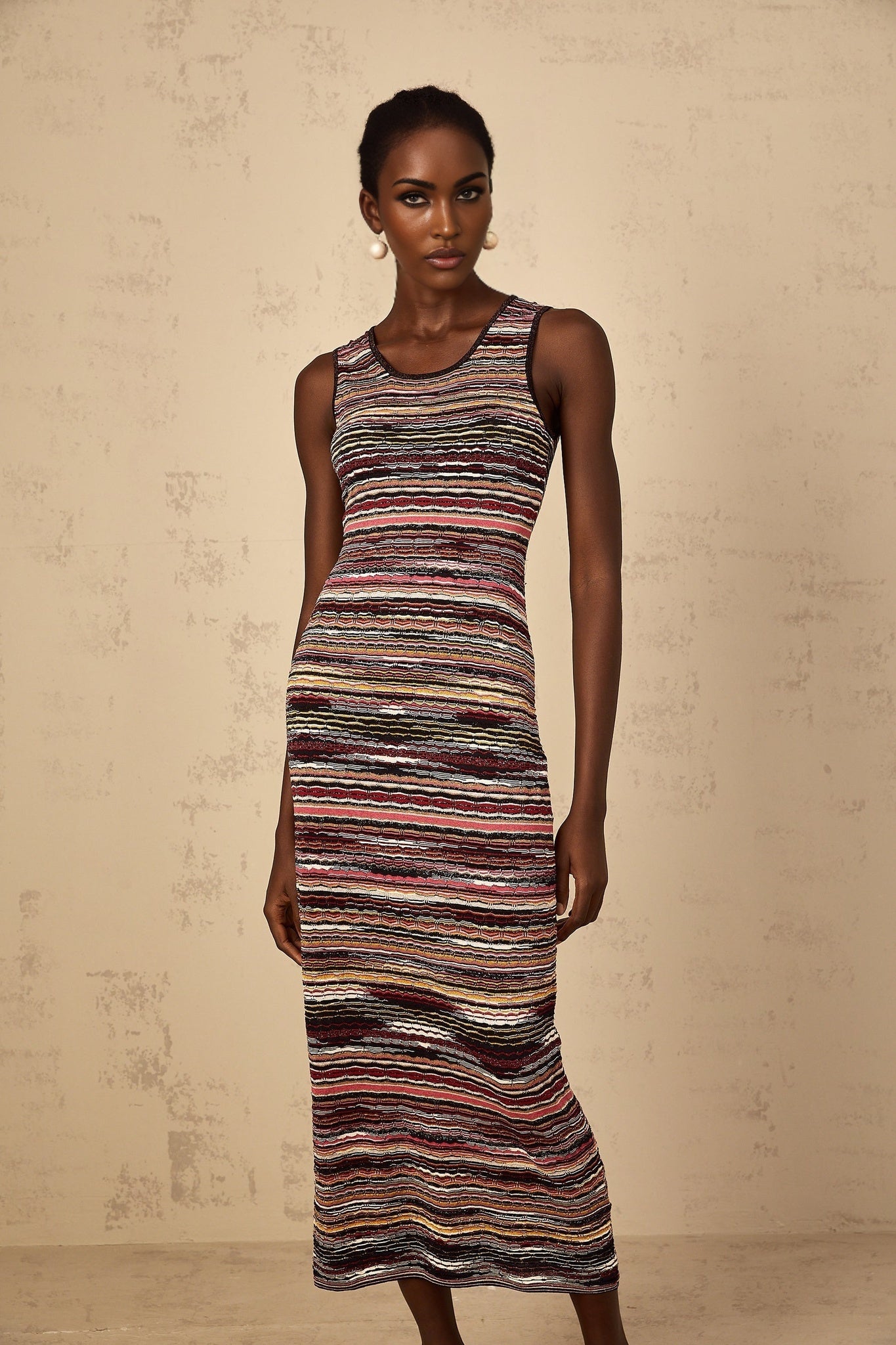 Woman wearing purple striped crochet knit midi dress with long sleeves and scoop neckline standing against plain background