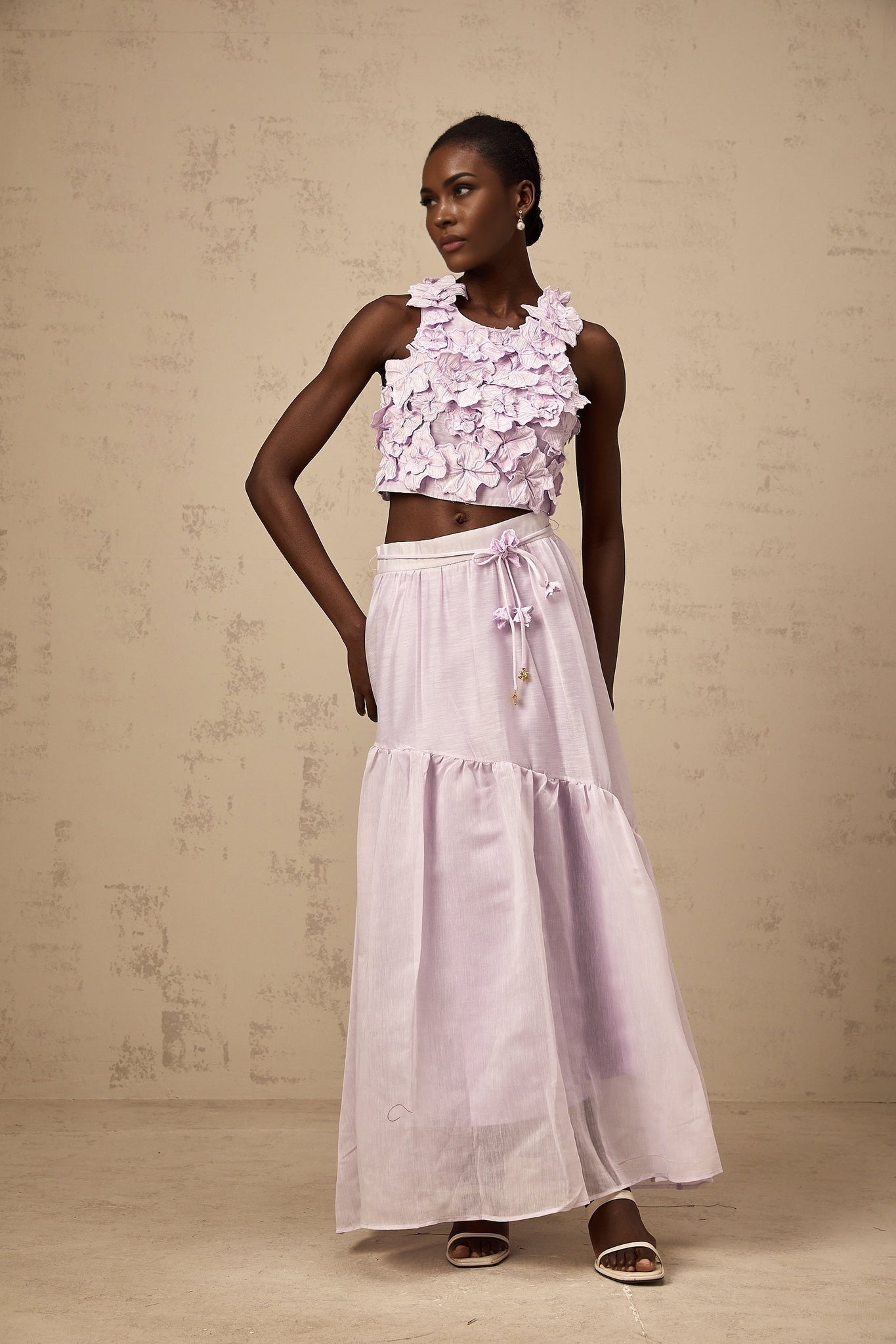 Woman wearing purple two piece outfit with floral pattern top and matching skirt
