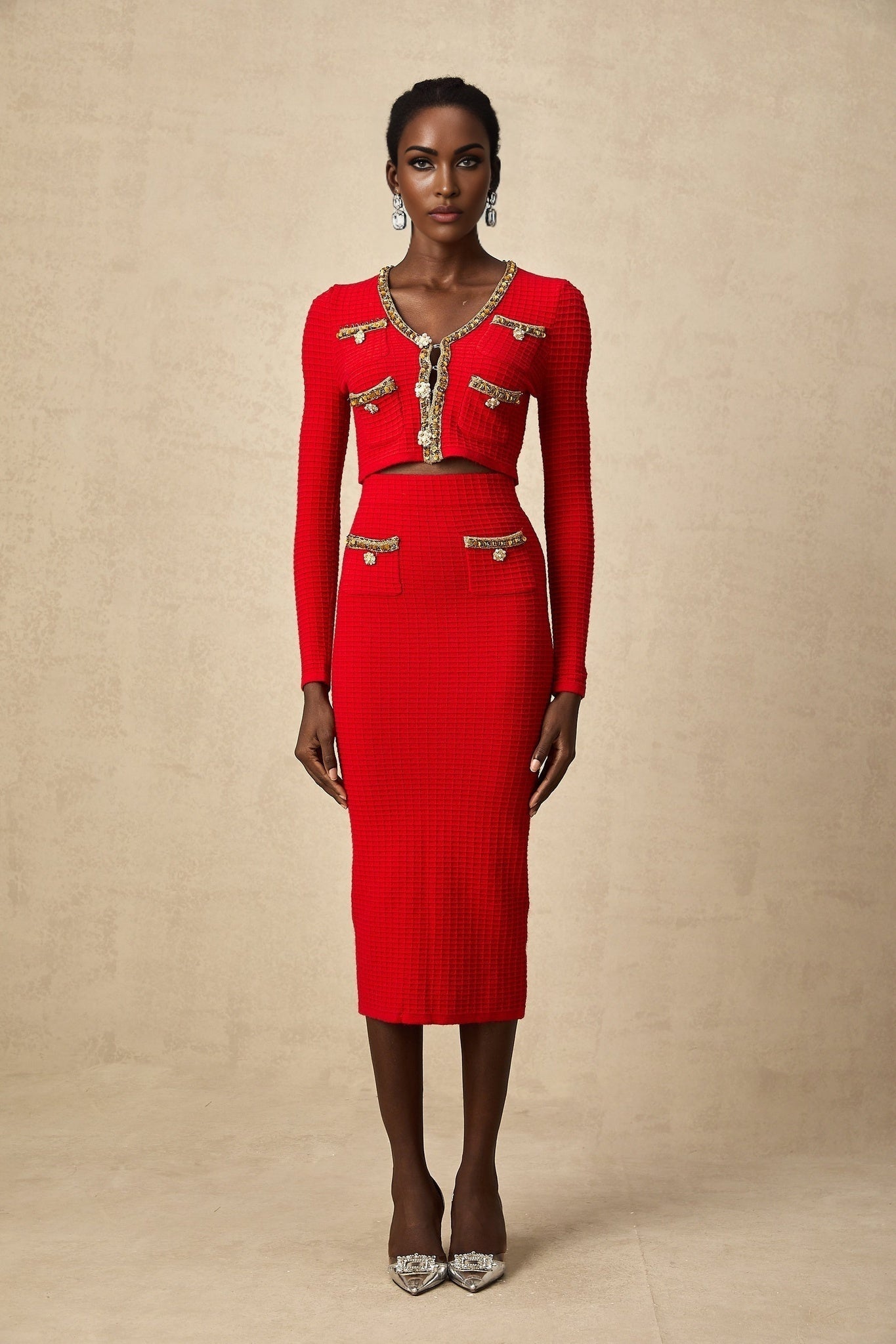 Woman wearing red knitted cardigan and matching skirt set with embellished details