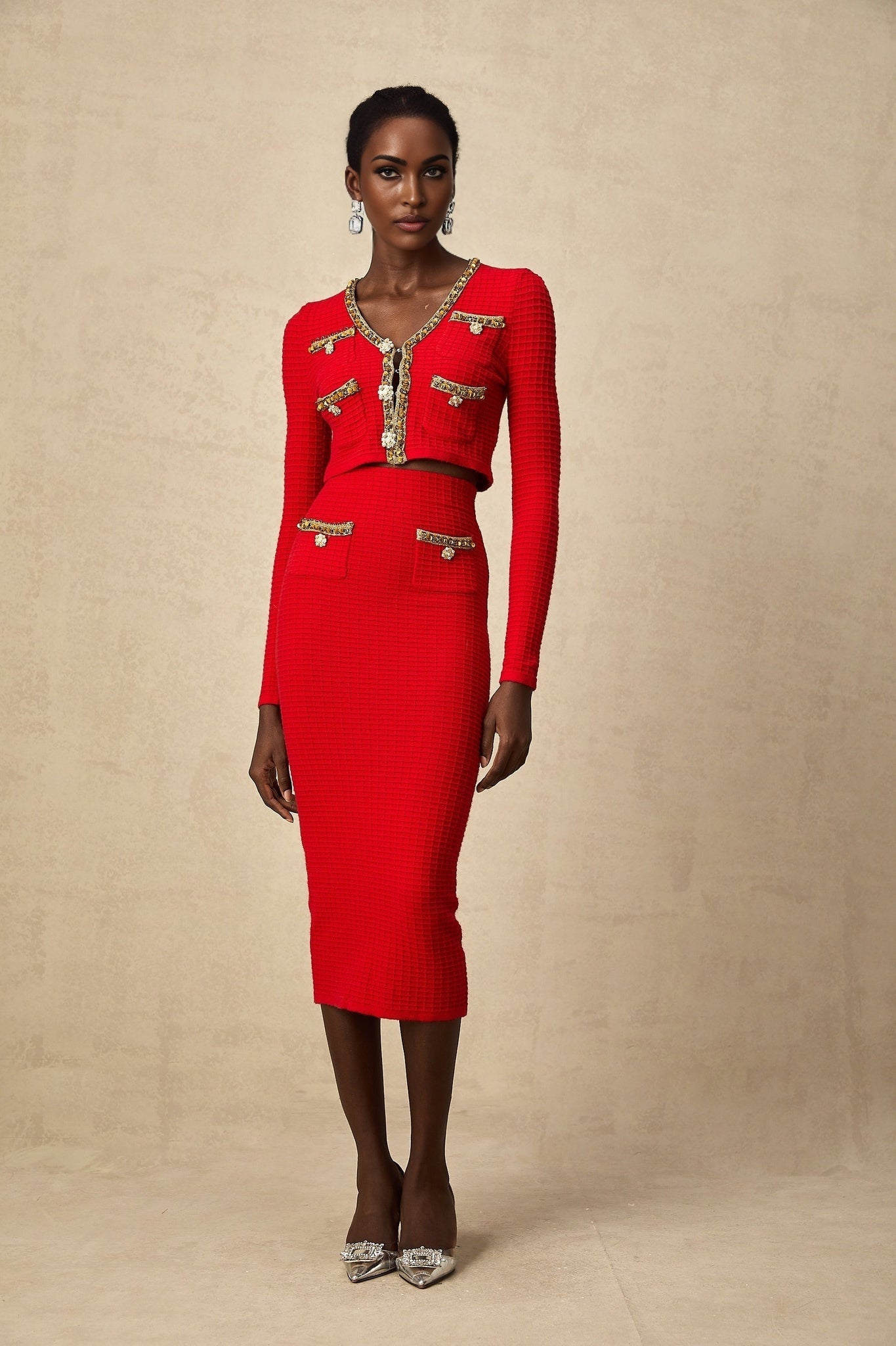Woman wearing red knitted cardigan and matching skirt set with embellishments