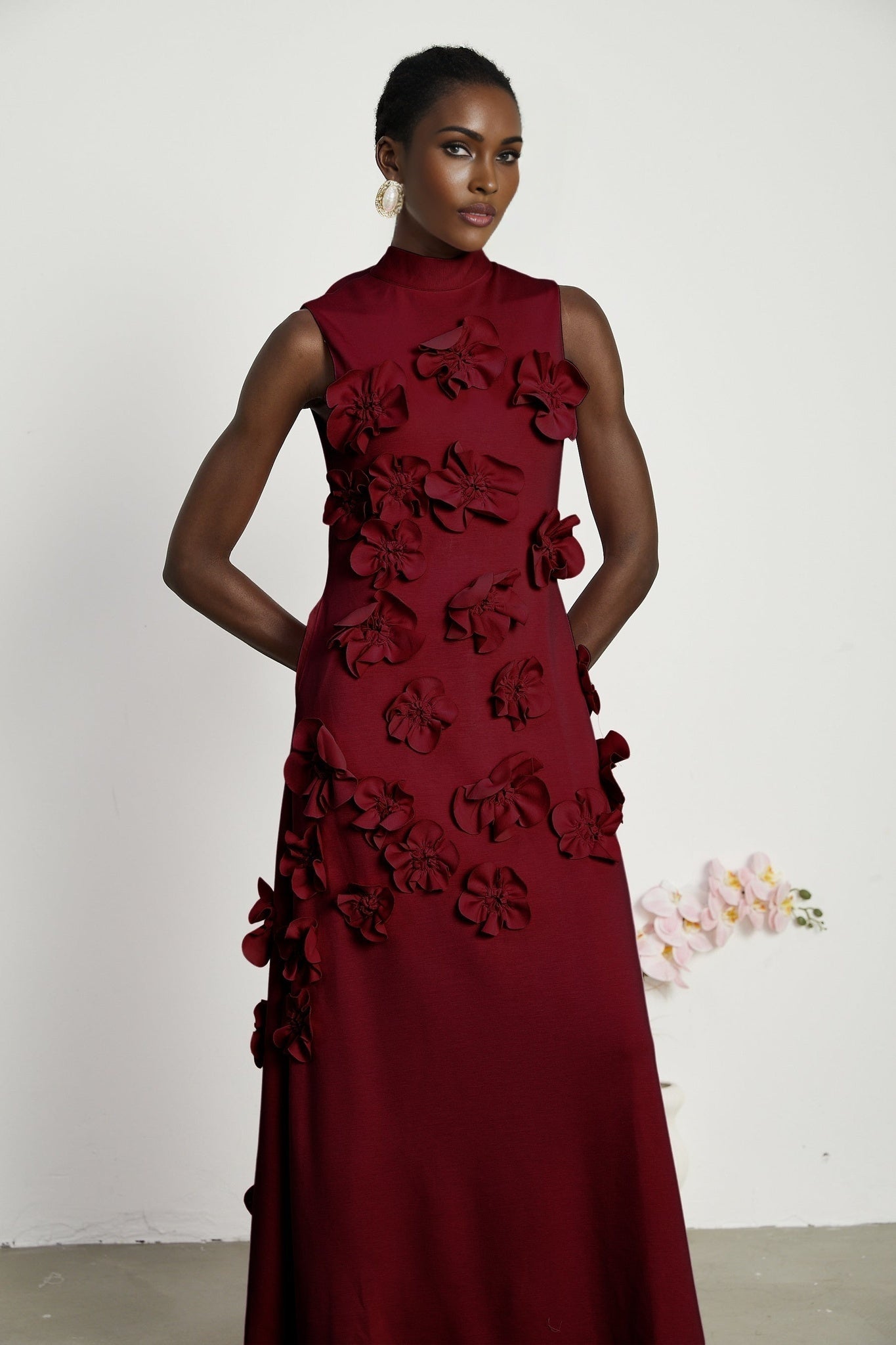 Woman wearing red sleeveless maxi dress with bow tie and faux flower embellishments
