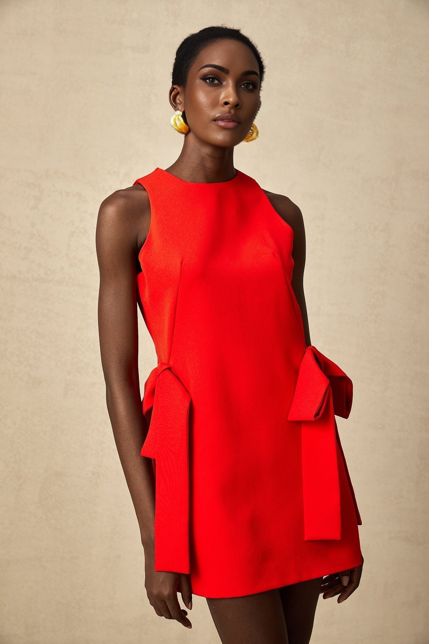 Woman wearing red sleeveless mini dress with bow detail